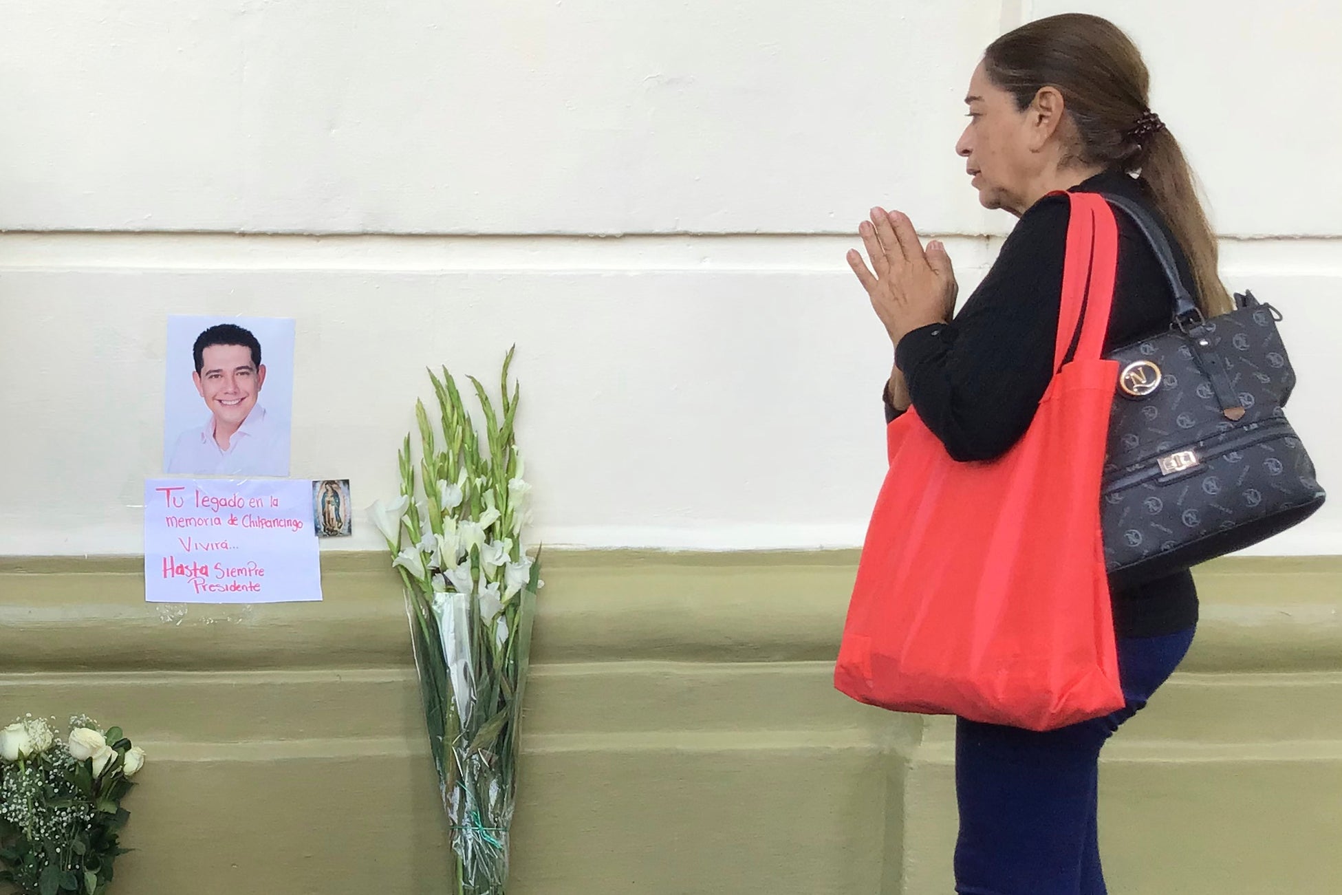 A supporter of slain Mayor Alejandro Arcos prays at the entrance of the municipal building one week after he took office