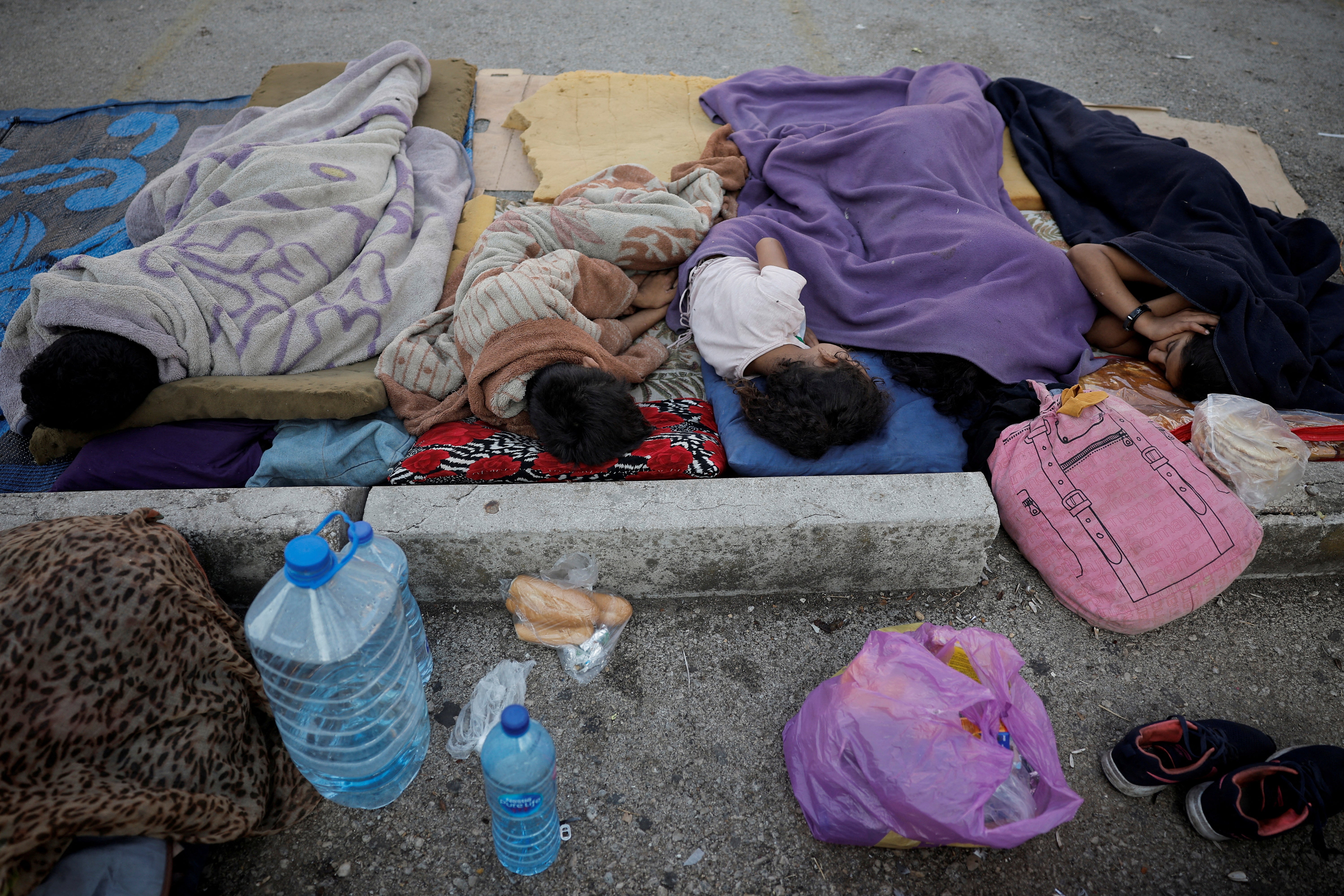 Five children sleep on the street next to bottles of water, carrier bags and bread amid fresh Israeli airstrikes on Beirut