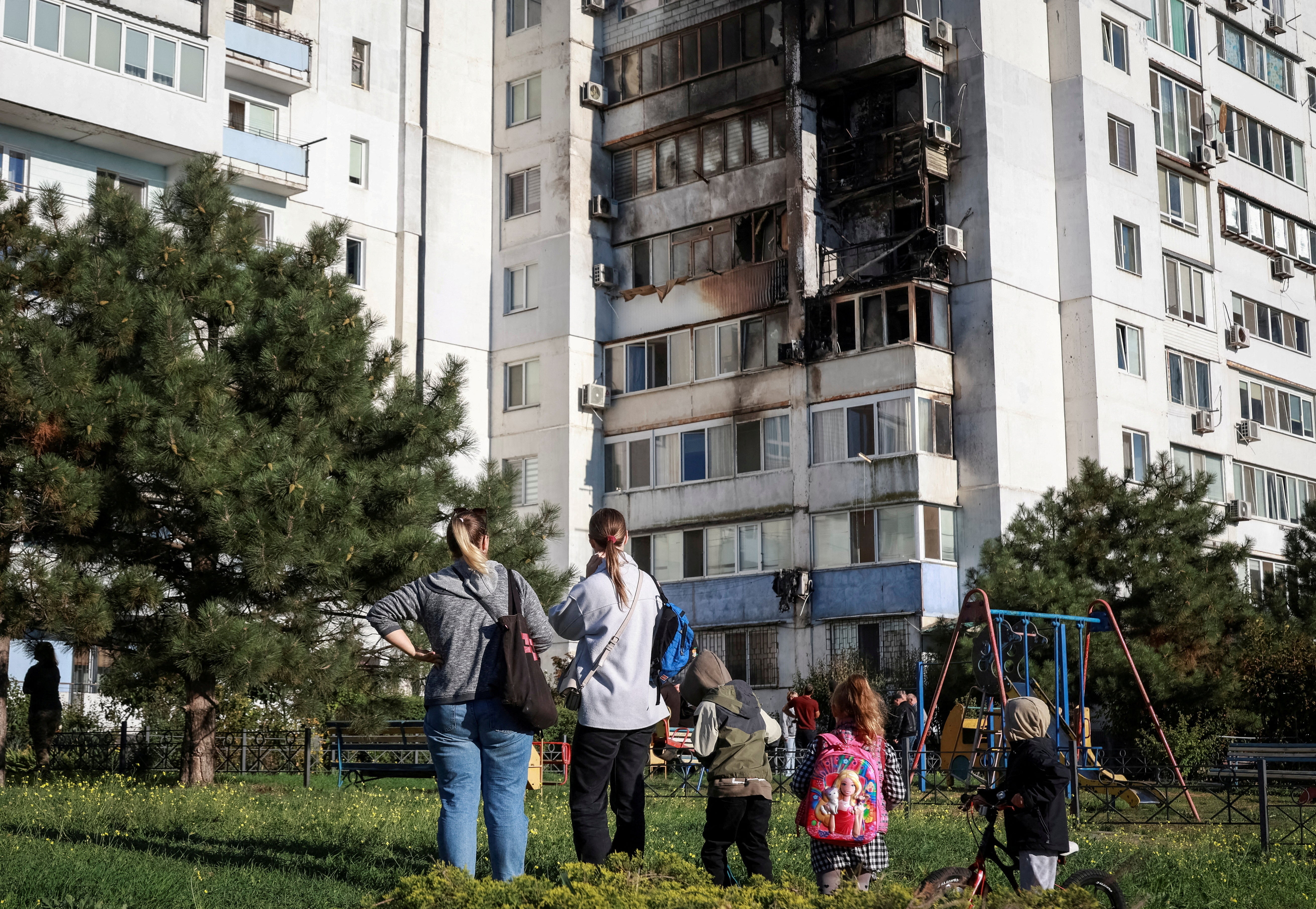 Locals stand at the site of a Russian drone strike in the city of Chornomorsk, Odesa region