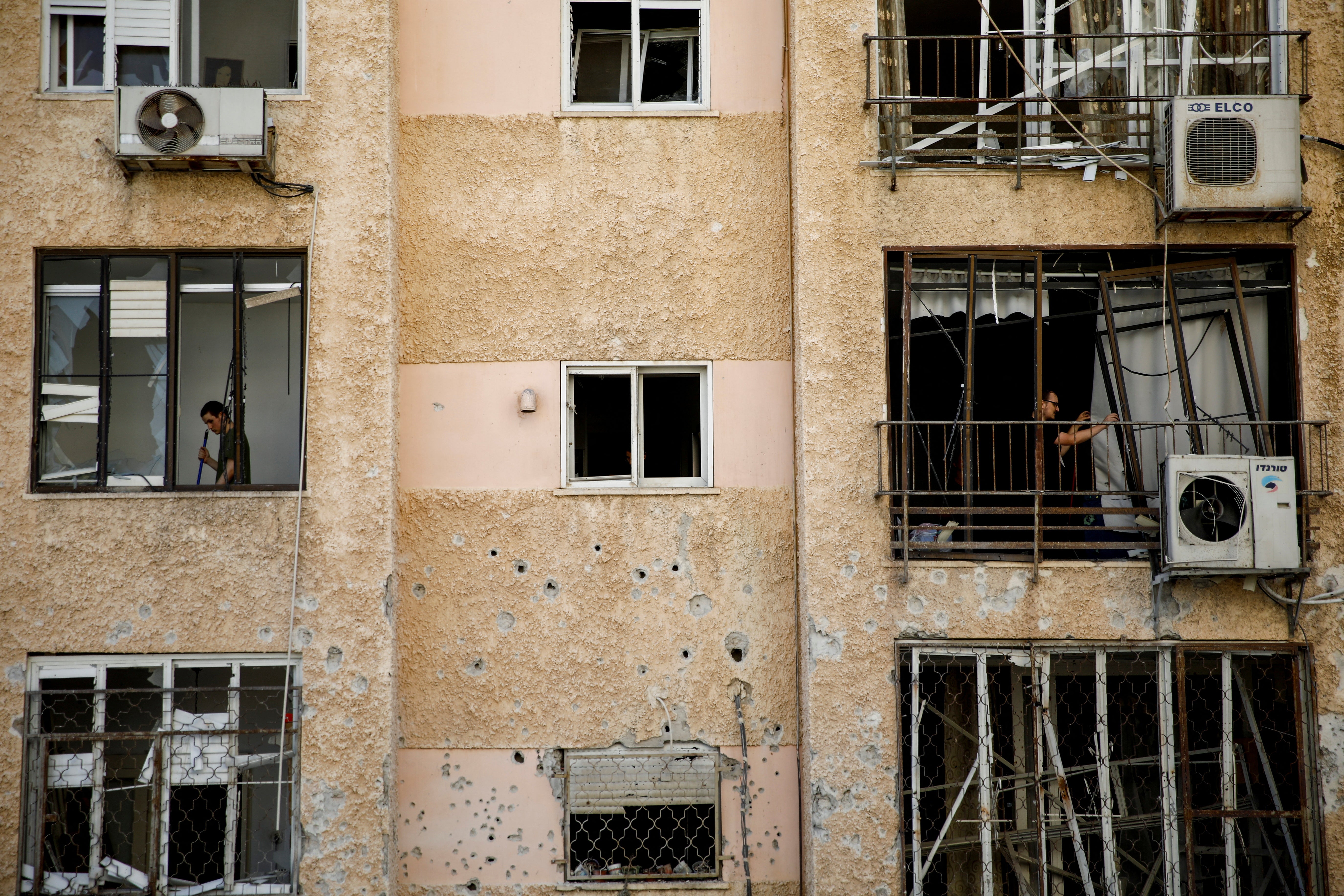 Israelis stand inside a building damaged by Hezbollah rocket fire in northern Israel on Tuesday