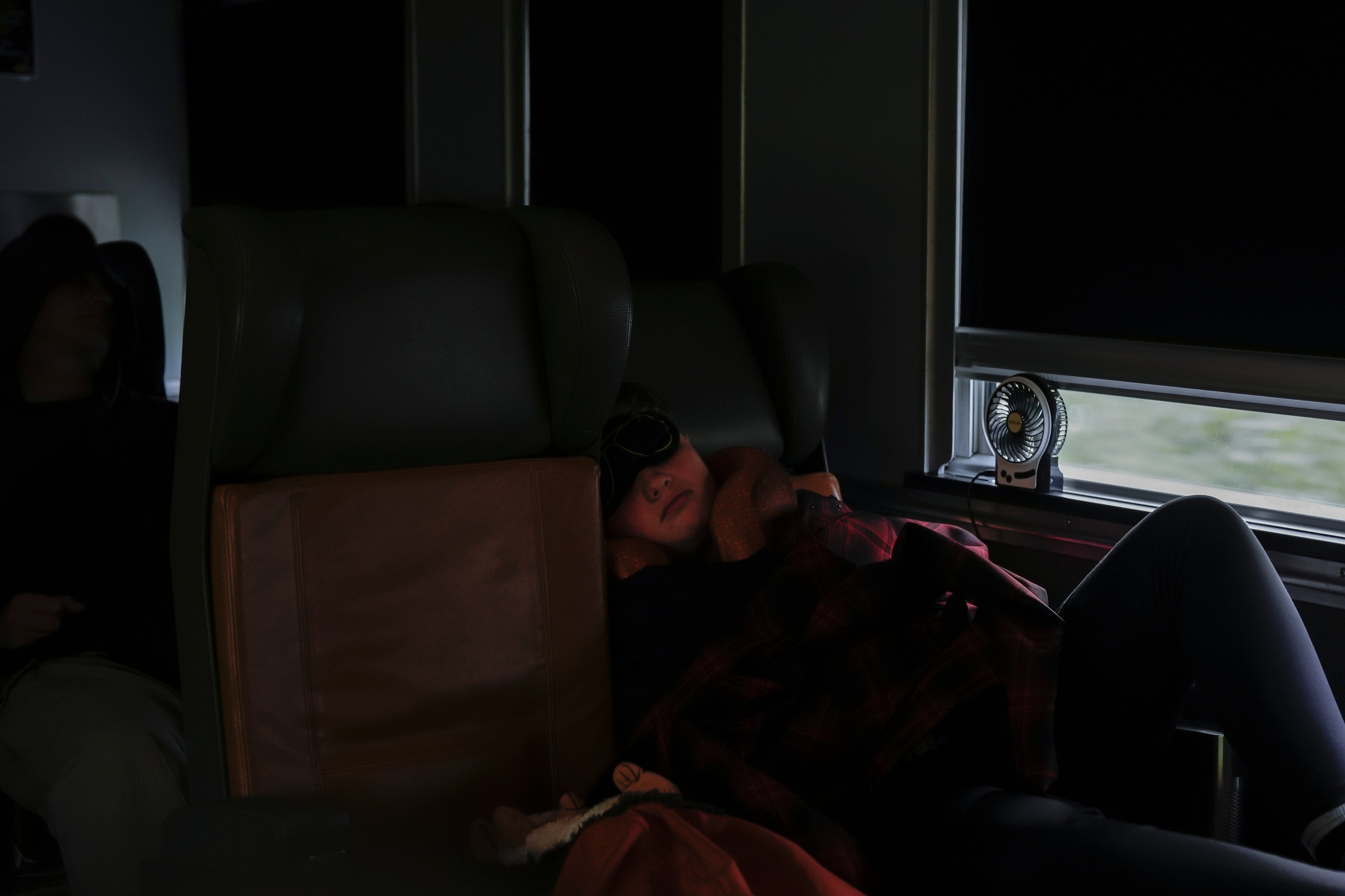 A passenger sleeps inside the economy car on a train Friday, Aug. 9, 2024, near Ilford