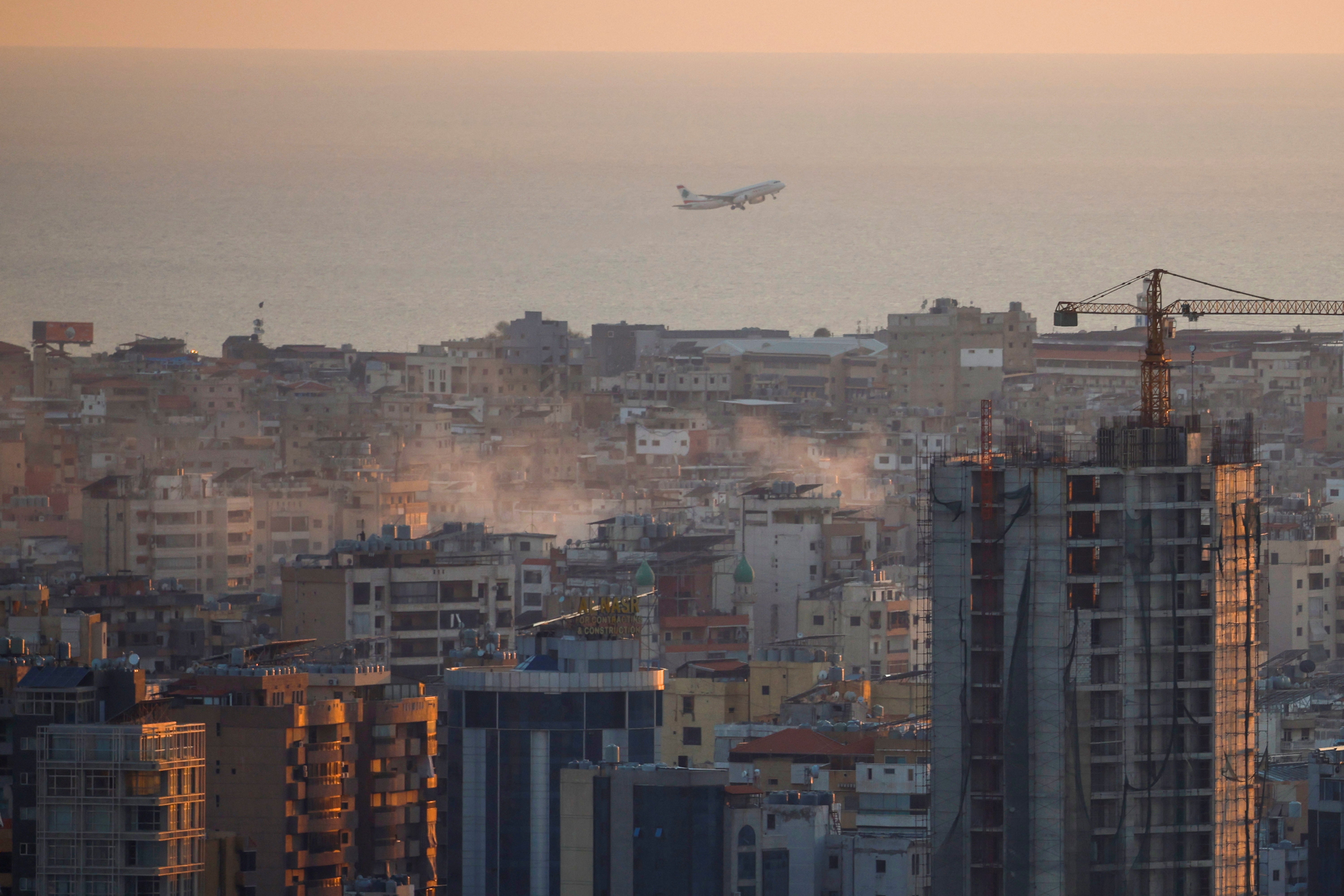 A commercial plane takes off from Beirut’s International Airport as smoke billows across the capital city following Israeli airstrikes