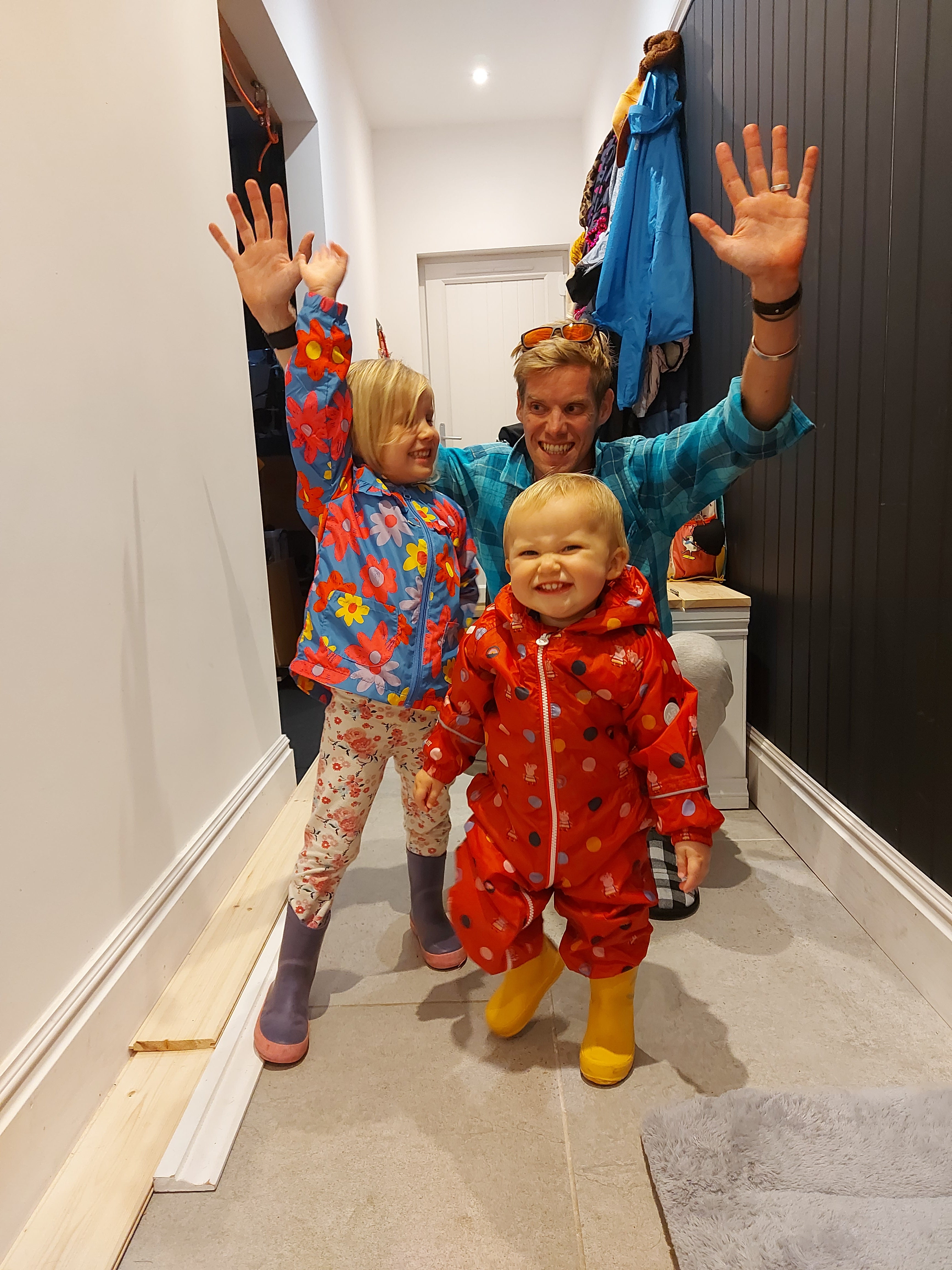 Jack kneeling in a hallway with his two children standing in front of him