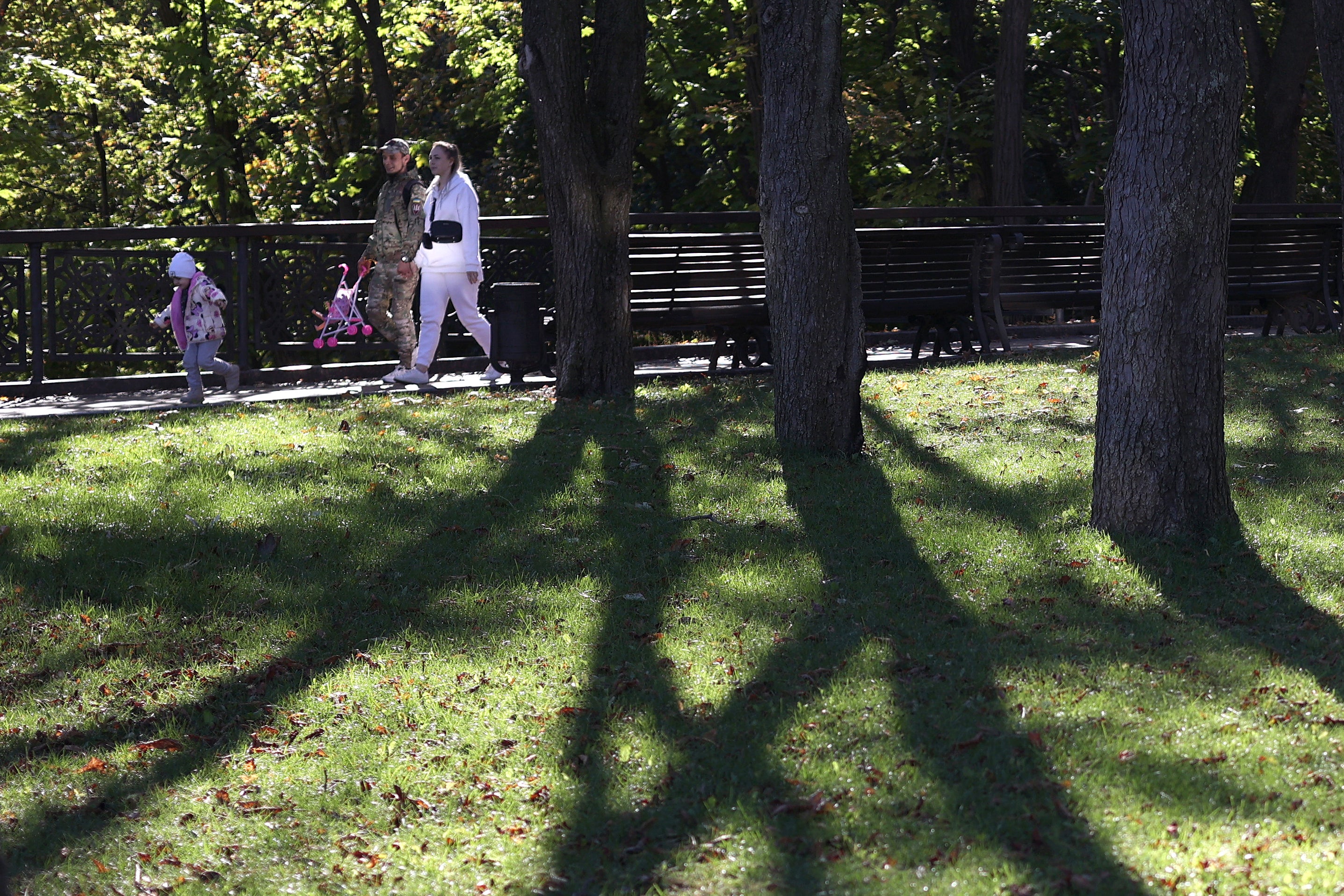 A Ukrainian serviceman and his family walk in a park on a sunny autumn day in central Kyiv