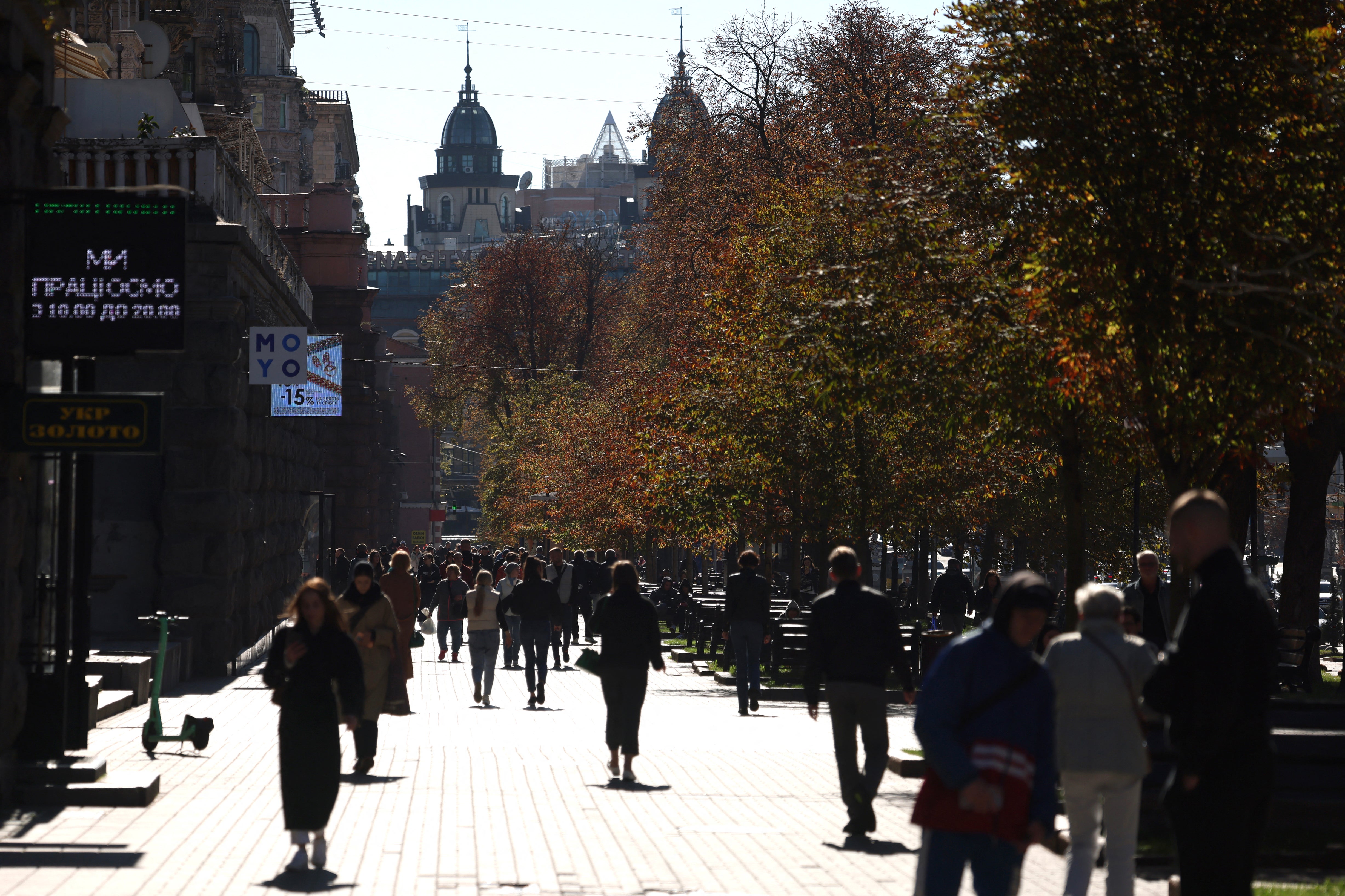 Local residents walk in a street on a sunny autumn day in central Kyiv yesterday