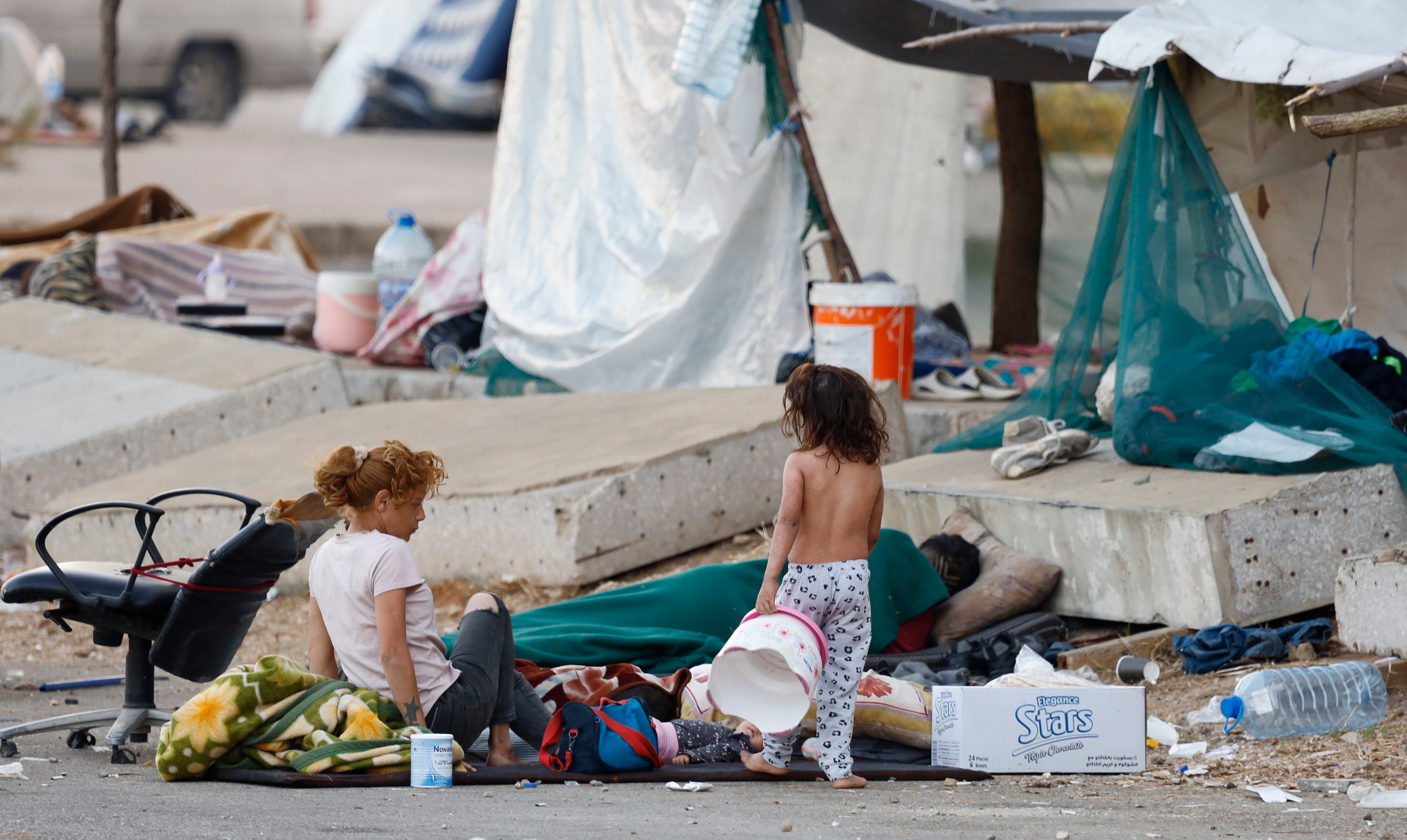 A family sits and sleeps on the ground in Beirut following Israeli airstrikes on the city