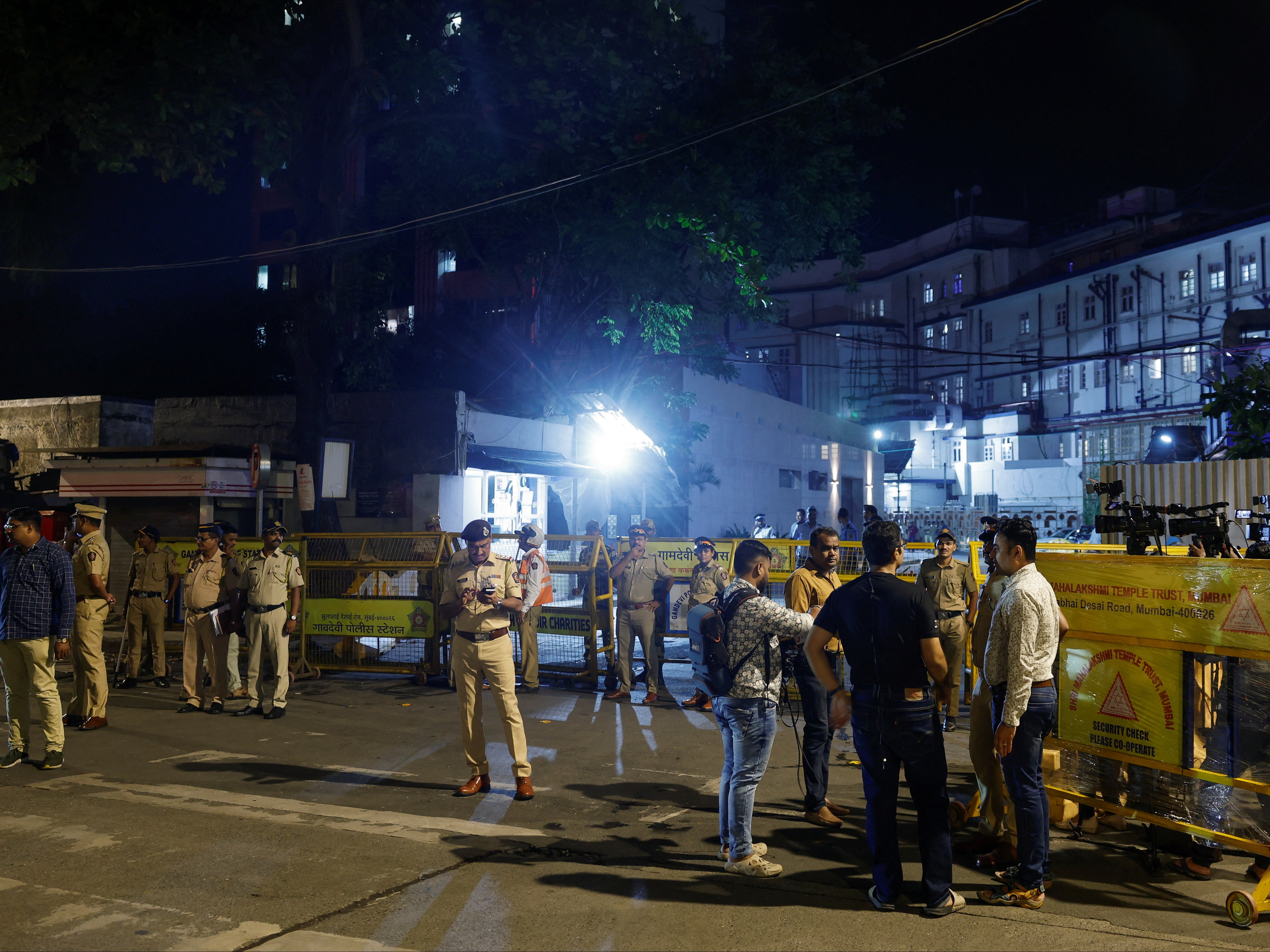 Law enforcement officers standing guard as media wait outside a hospital where former chairman of Tata Group, Ratan Tata passed away in Mumbai, India, 10 October 2024