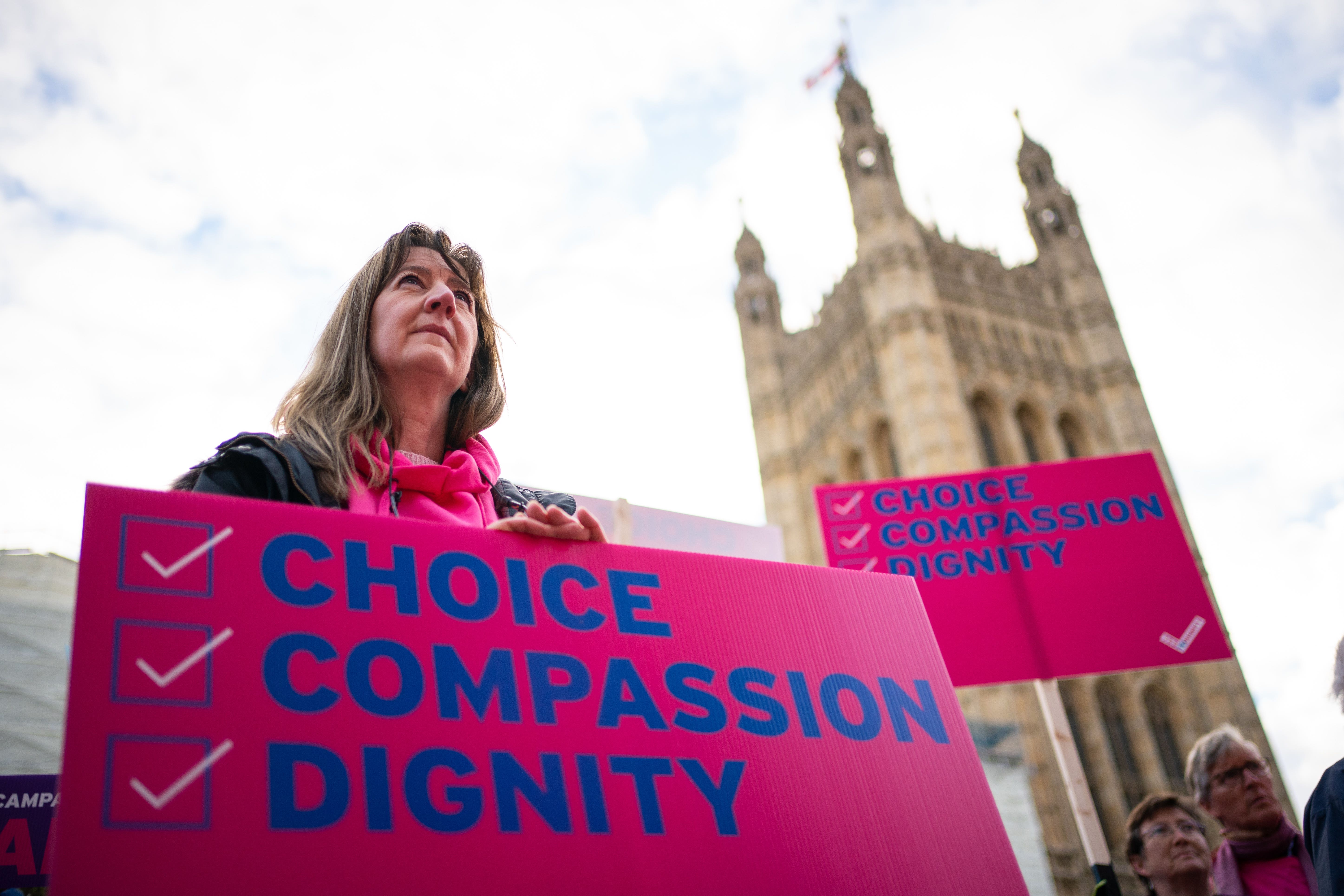 A woman with a pro-assisted dying placard outside Parliament