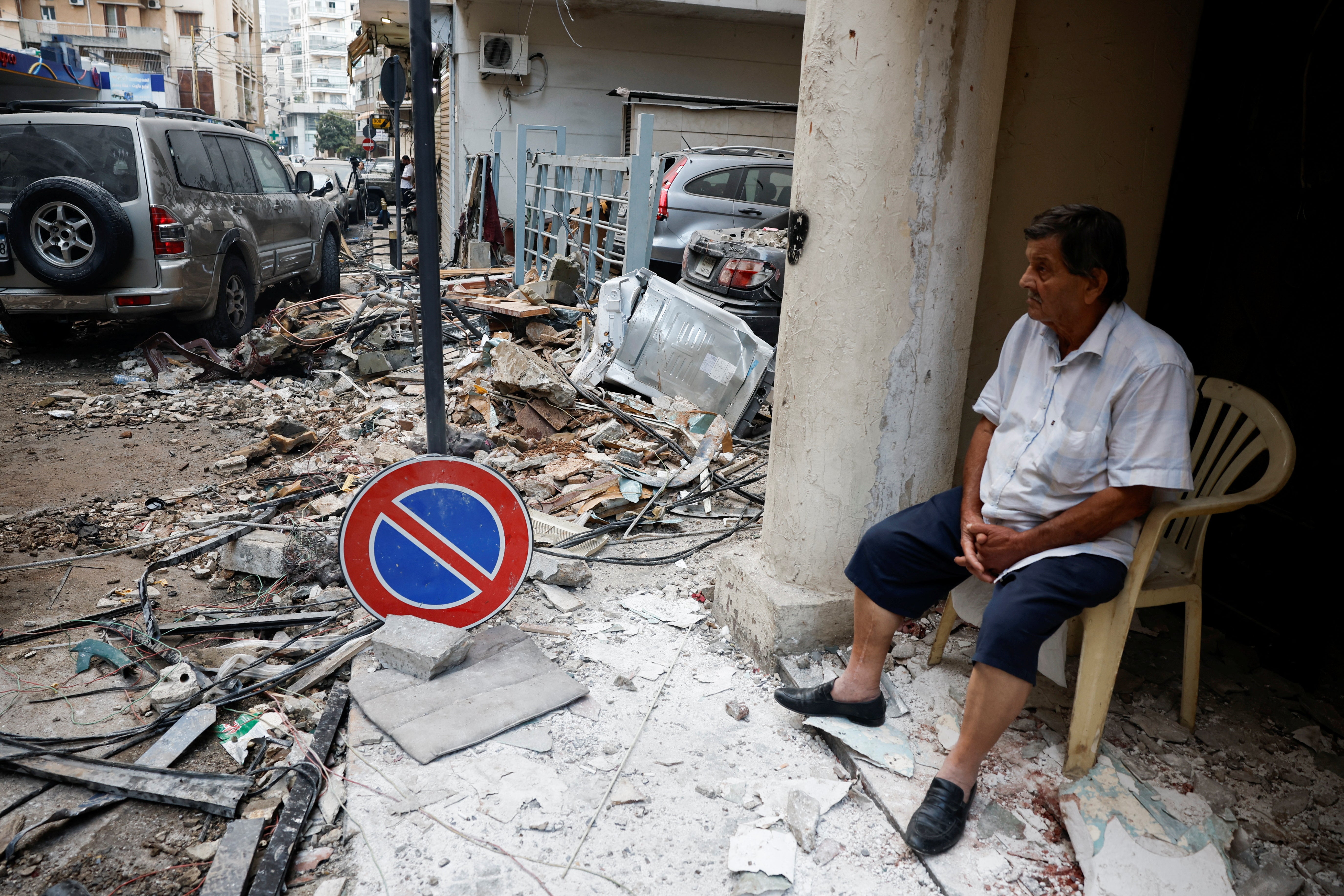 A man sits next to the rubble at the site of an Israeli air strike in Lebanon