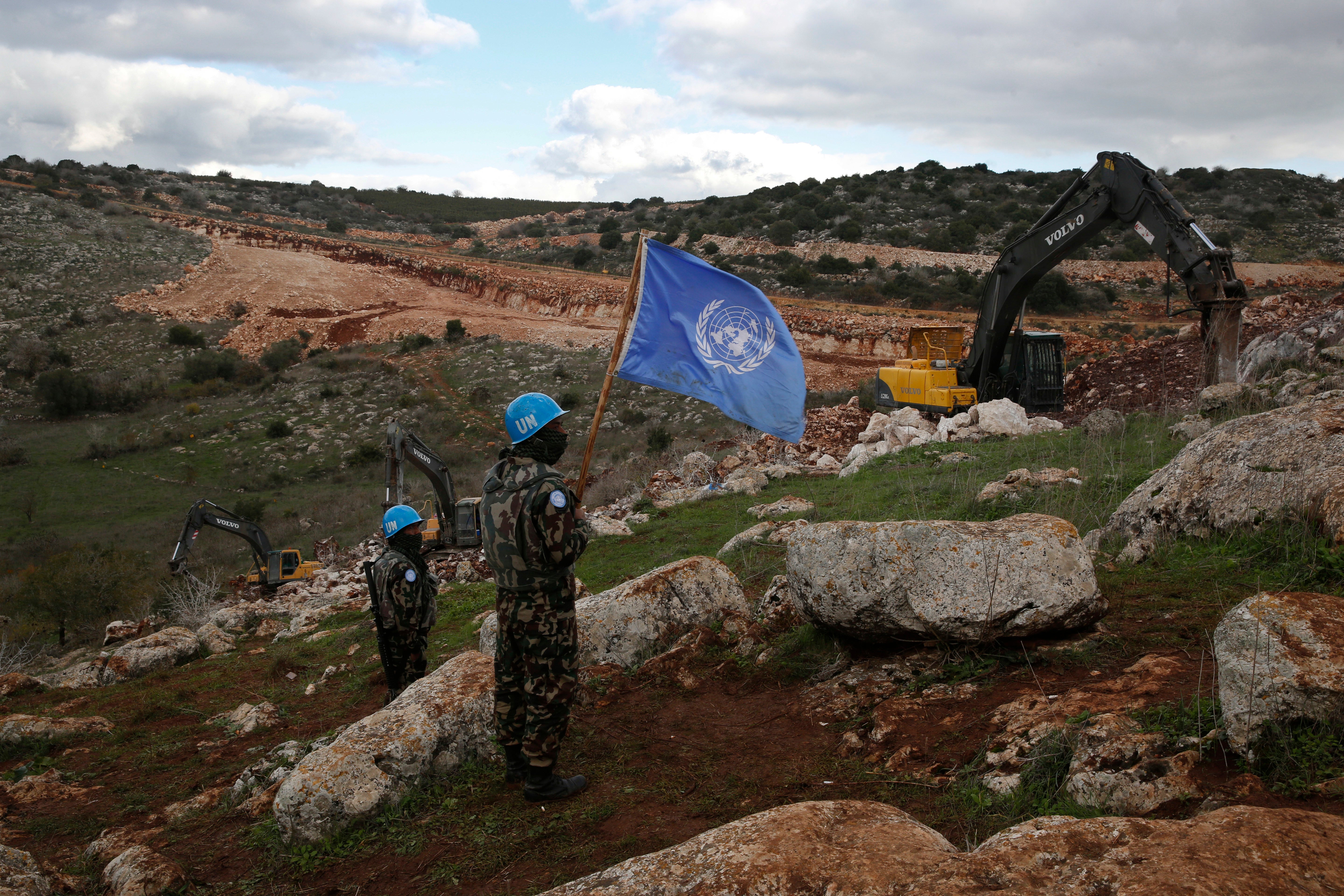 UN peacekeepers hold their flag, as they observe Israeli excavators attempt to destroy tunnels built by Hezbollah, near the southern Lebanese-Israeli border village of Mays al-Jabal, Lebanon, Dec. 13, 2019