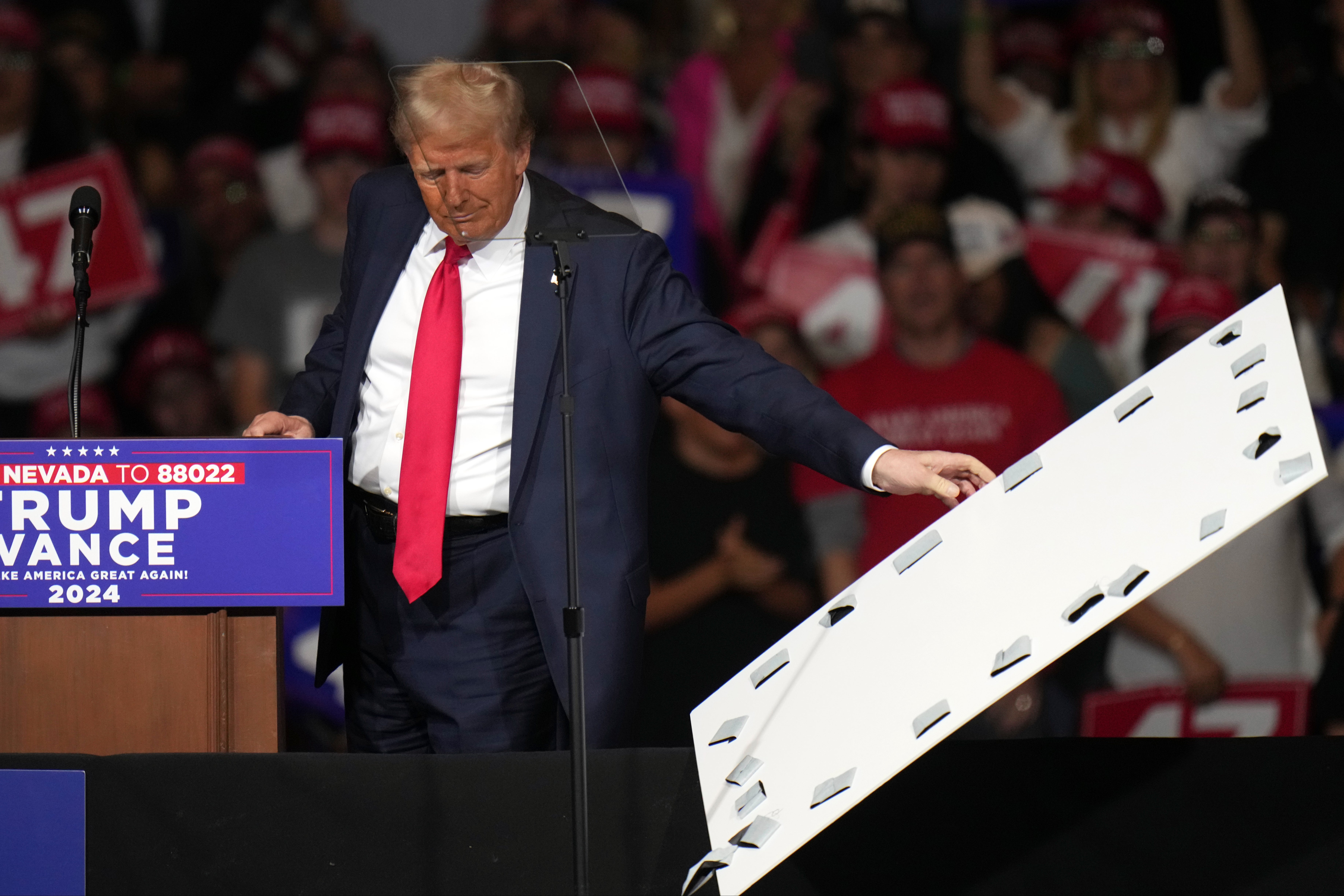 Former president Donald Trump removed signage that fell on top of his teleprompter at a rally in Reno, Nevada