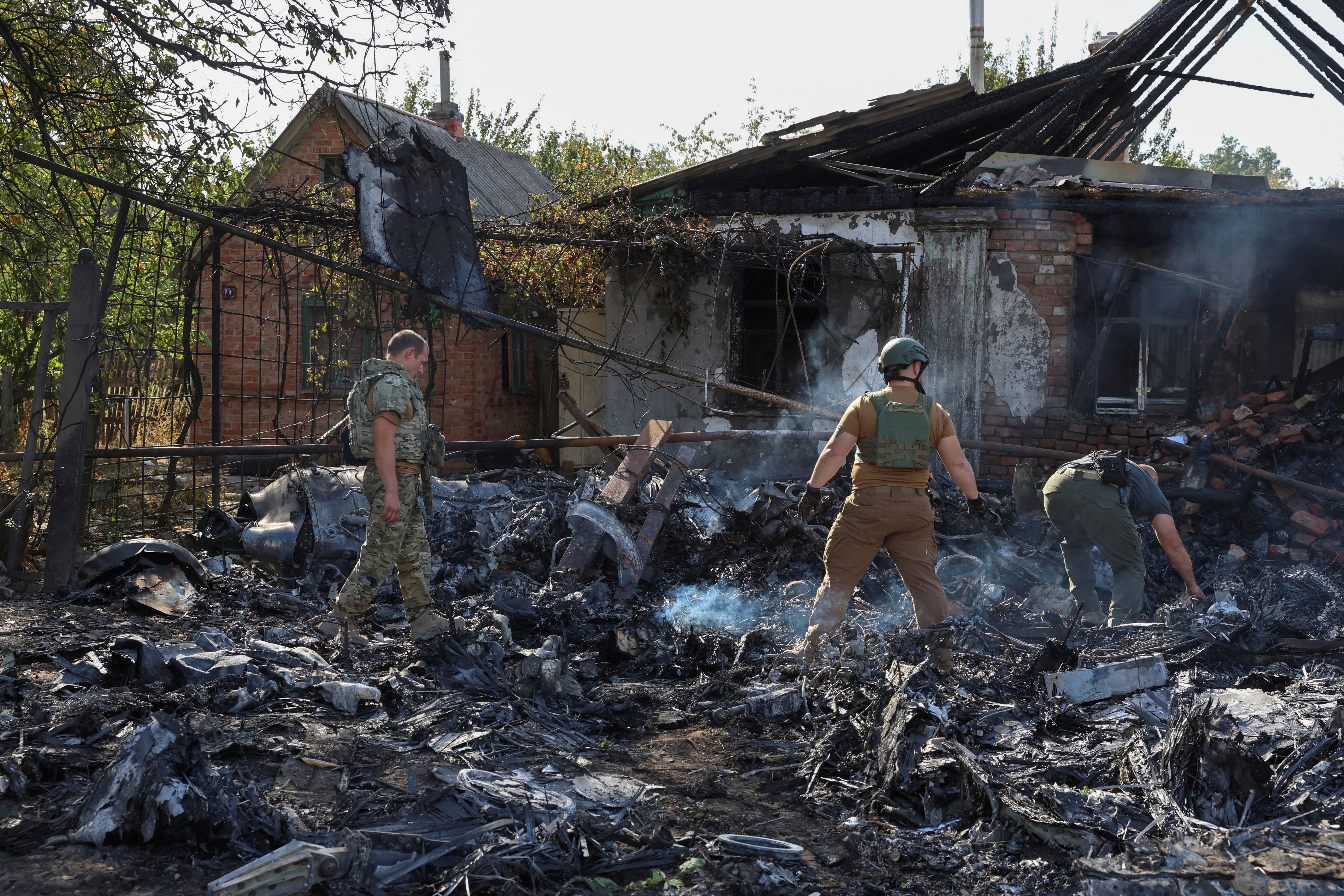 Ukrainian service members inspect parts of a Russian aerial vehicle, which local authorities assume to be a newest heavy unmanned aerial vehicle S-70 Okhotnik (Hunter) or variation of Sukhoi fighting jet, is seen in residential area of the town of Kostintynivka after it was shot down, amid Russia's attack on Ukraine, in Donetsk region