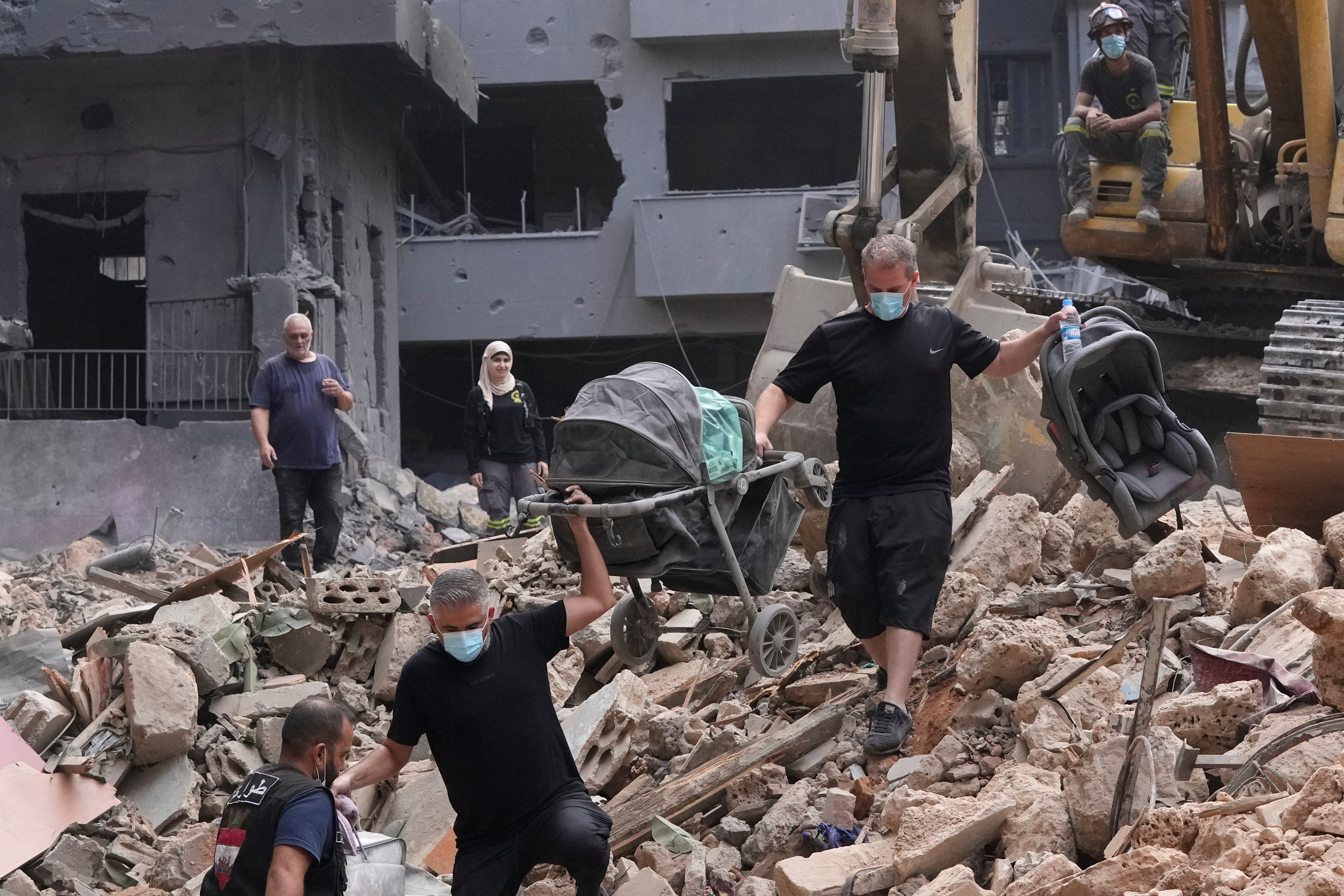 Residents of an apartment complex struck by an Israeli airstrike return to collect their belongings in Beirut on 12 October 2024