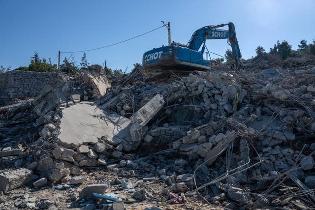 <p>An excavator stands atop the rubble of a house destroyed by an Israeli airstrike in which three people are claimed to have died on Sunday in Deir Billa, Lebanon</p>