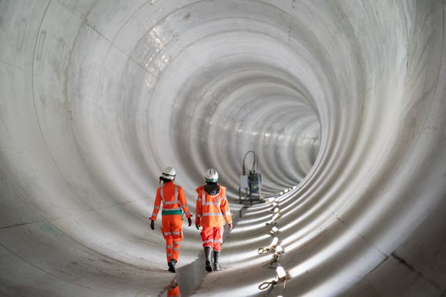 Construction workers walk in a completed section of the main tunnel of London’s new Thames Tideway Tunnel or ‘super sewer’ (Dominic Lipinski/PA)