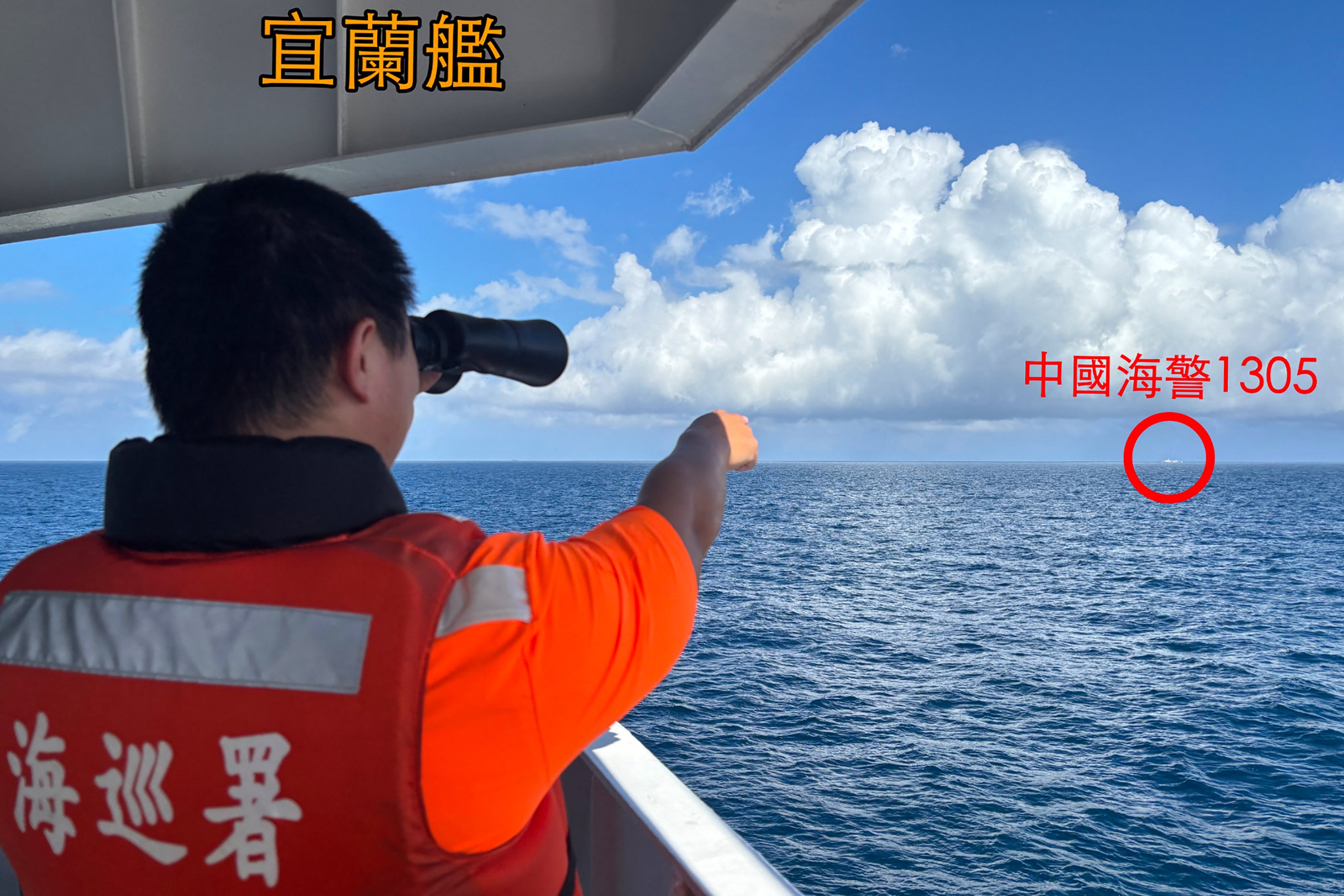 A Taiwanese coast guard personnel on a patrol ship off Pengjia Islet points to a Chinese ship sailing outside the island’s territorial waters on 14 October 2024