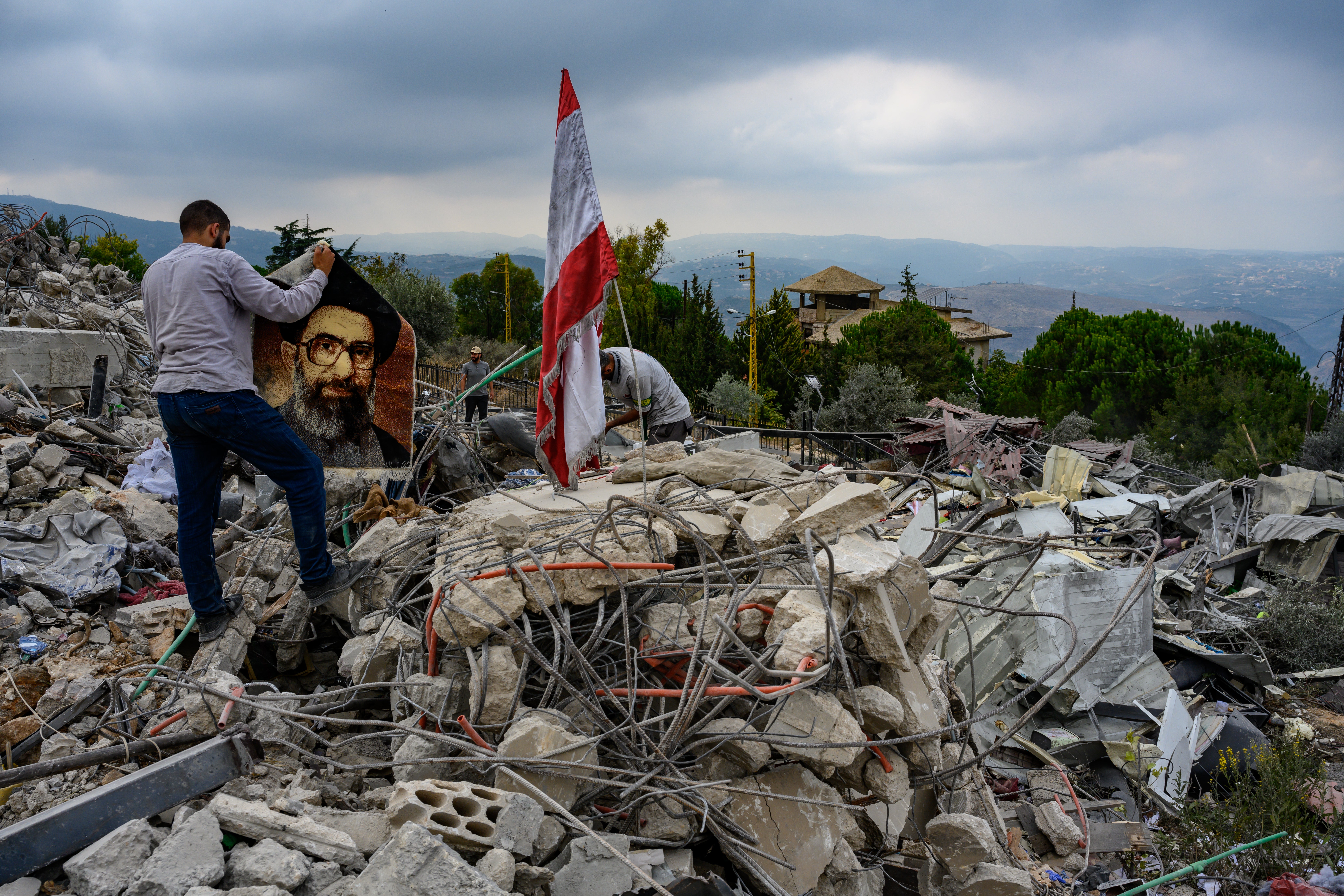 A local resident holds a prayer rug with an image of Iran’s supreme leader Ali Khamenei amid the rubble that remains from an Israeli airstrike