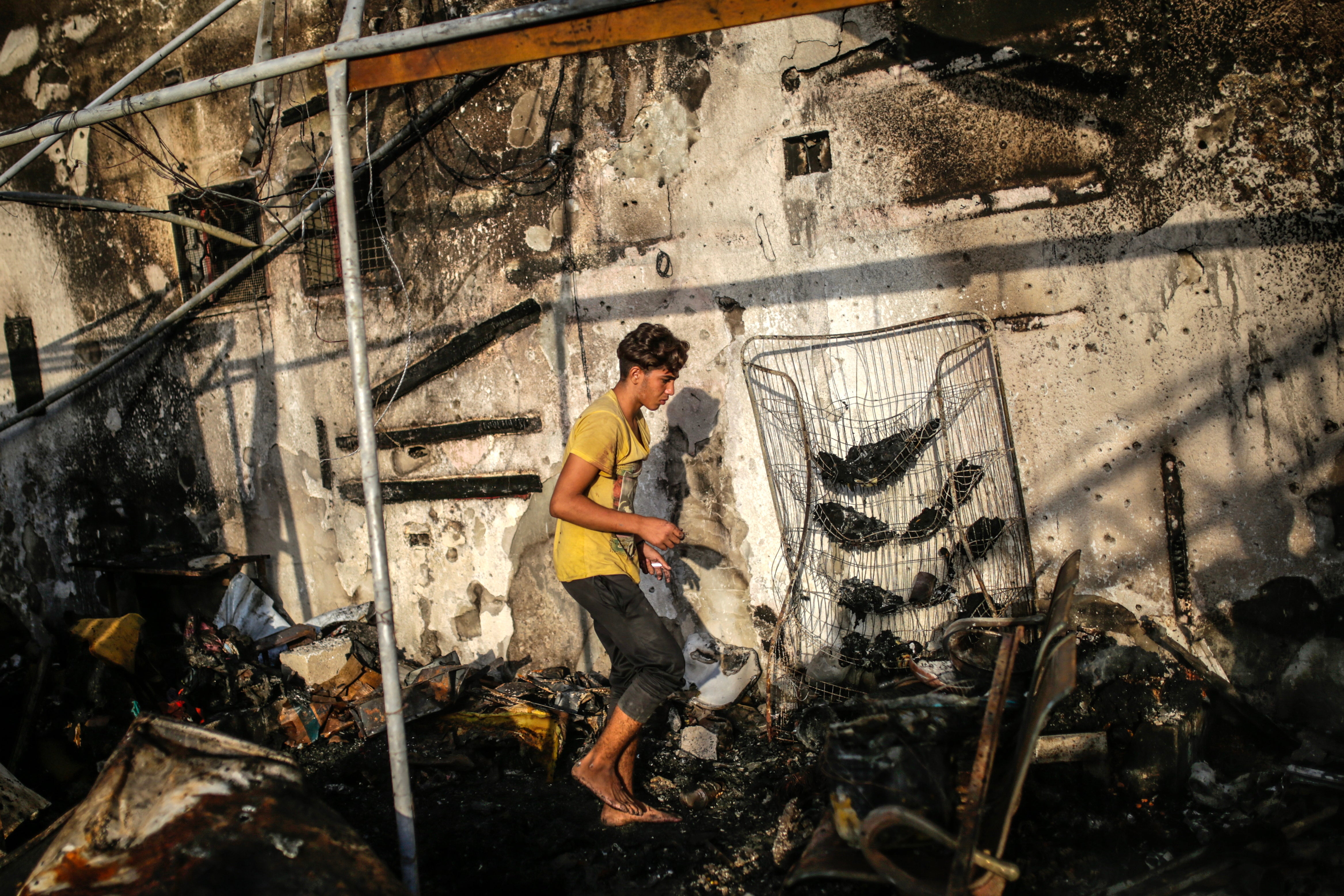 A Palestinian walks bare foot over ash and rubble following an Israeli airstrike on the area of a refugee camp