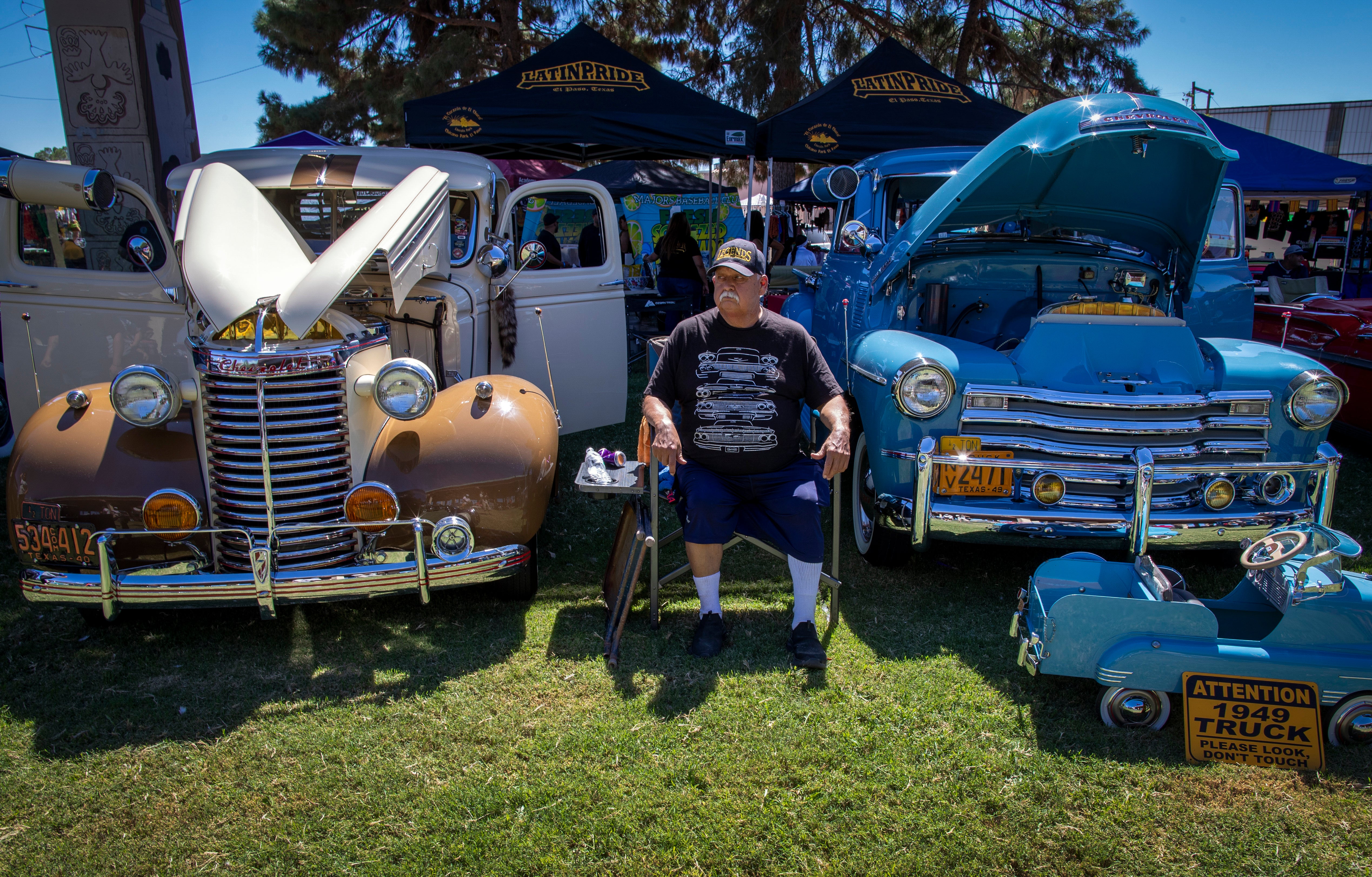 Santos Gonzalez sits between a 1939 and a 1949 Chevy vintage cars during a lowrider exhibition