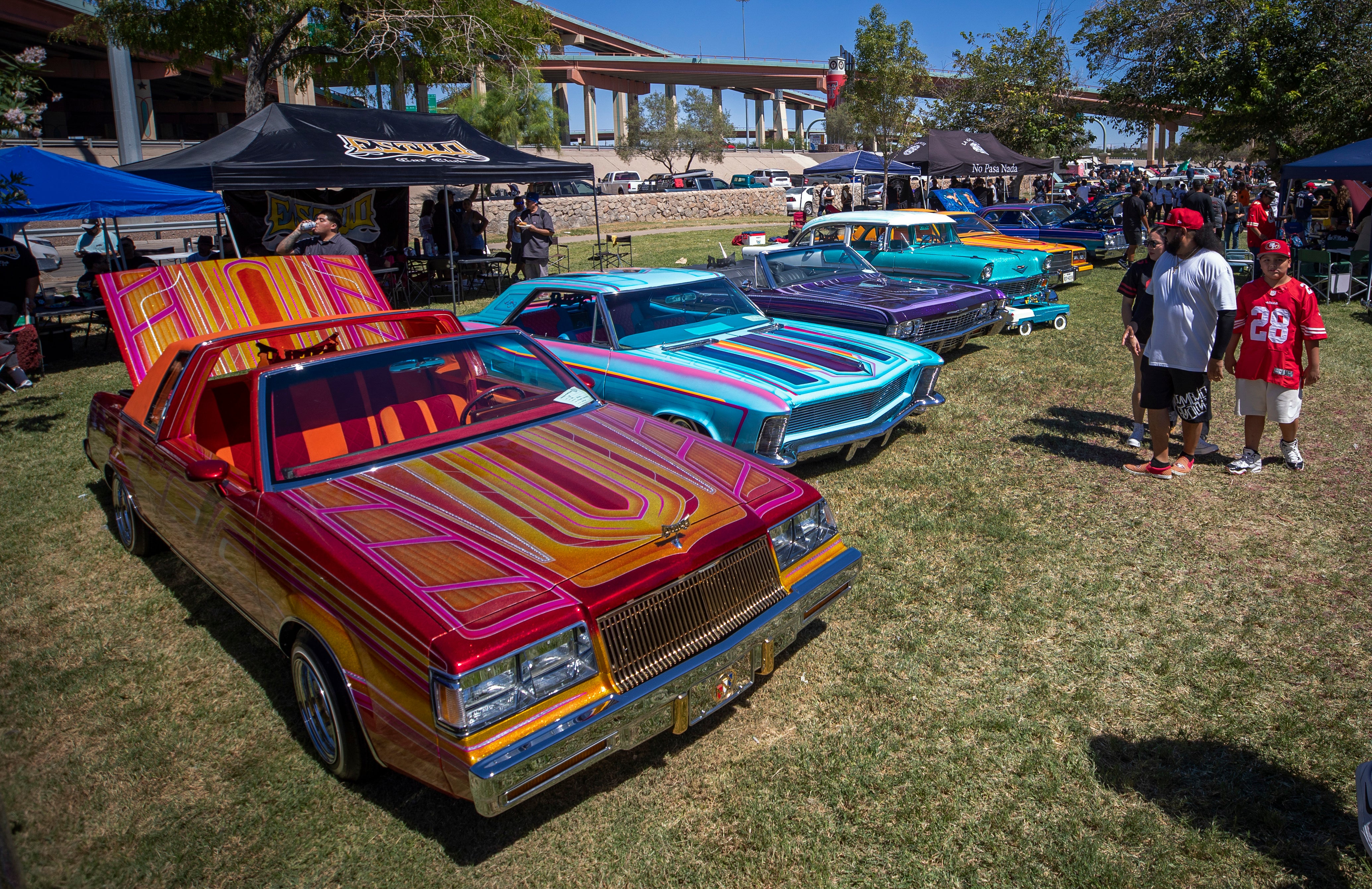 A family looks at vintage cars during a lowrider exhibition for the 20th anniversary of Lincoln Park in El Paso