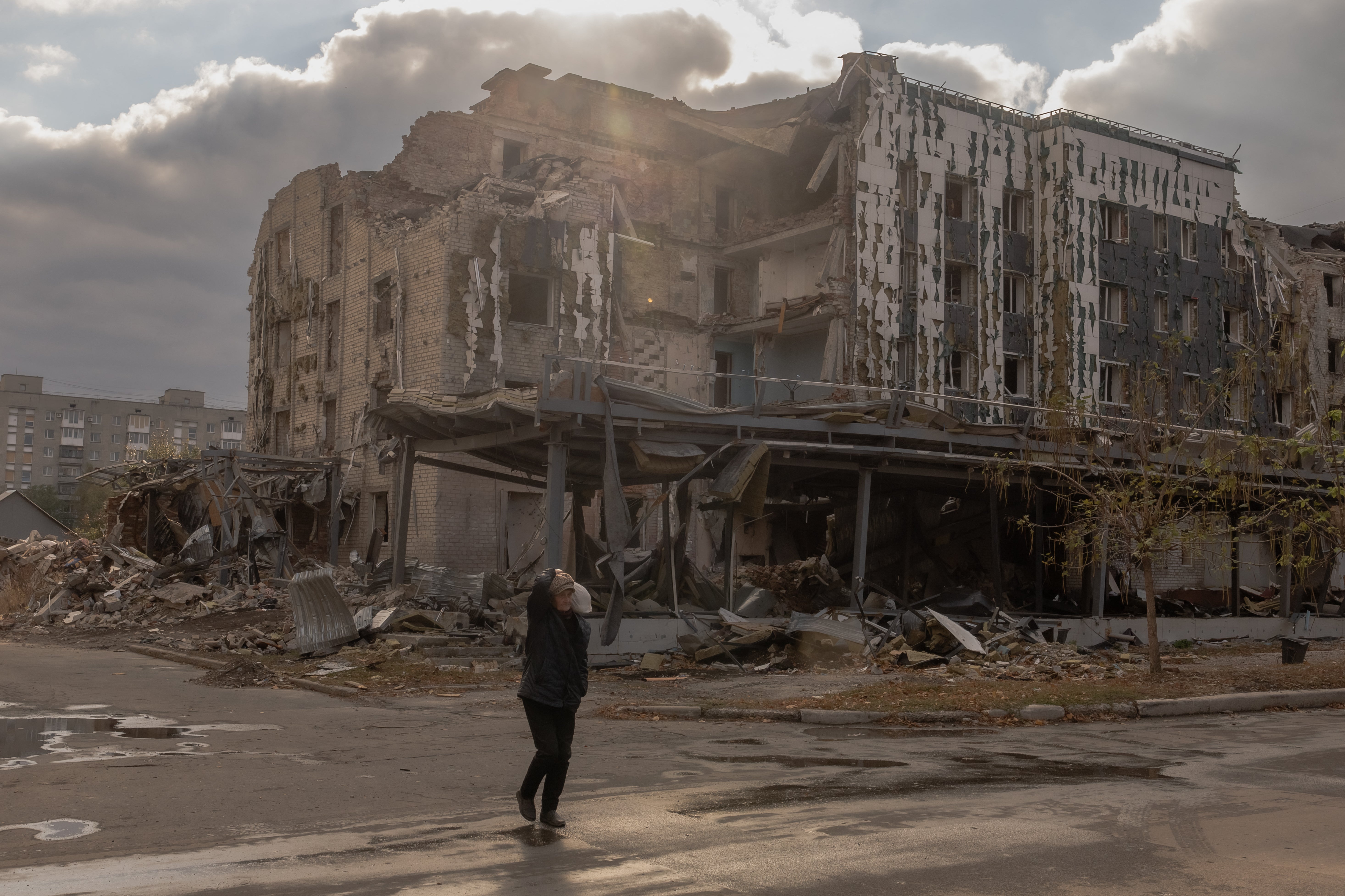 An elderly woman walks past damaged as a result of shelling buildings, in Pokrovsk, the eastern Donetsk region