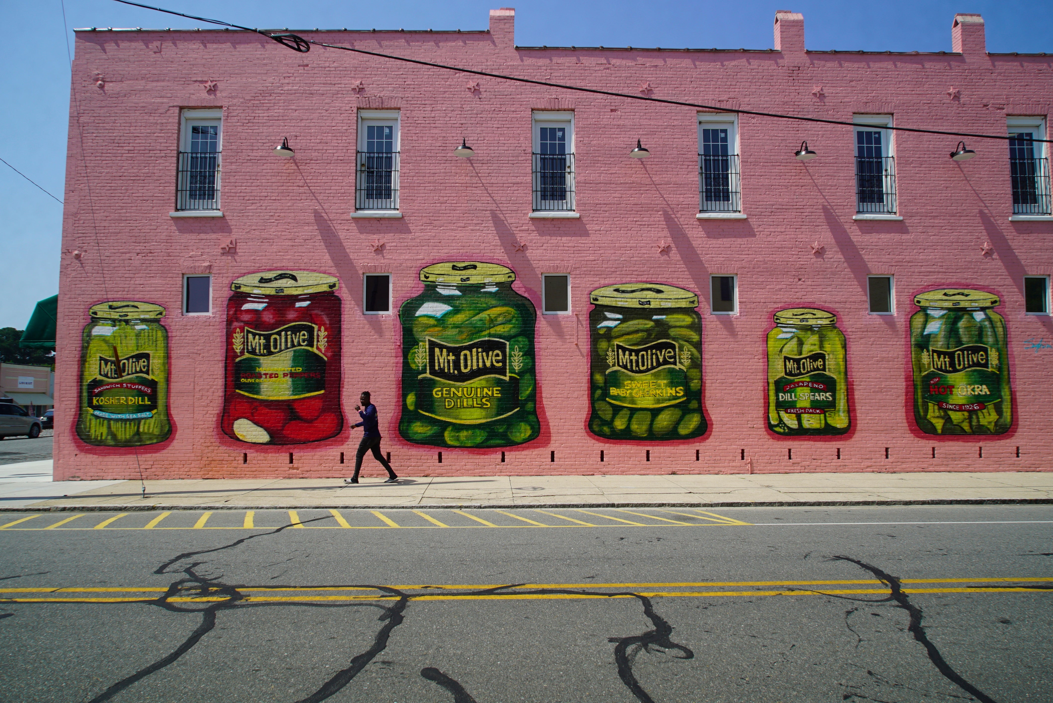 A man walks past a mural of various pickle products in Mount Olive, N.C