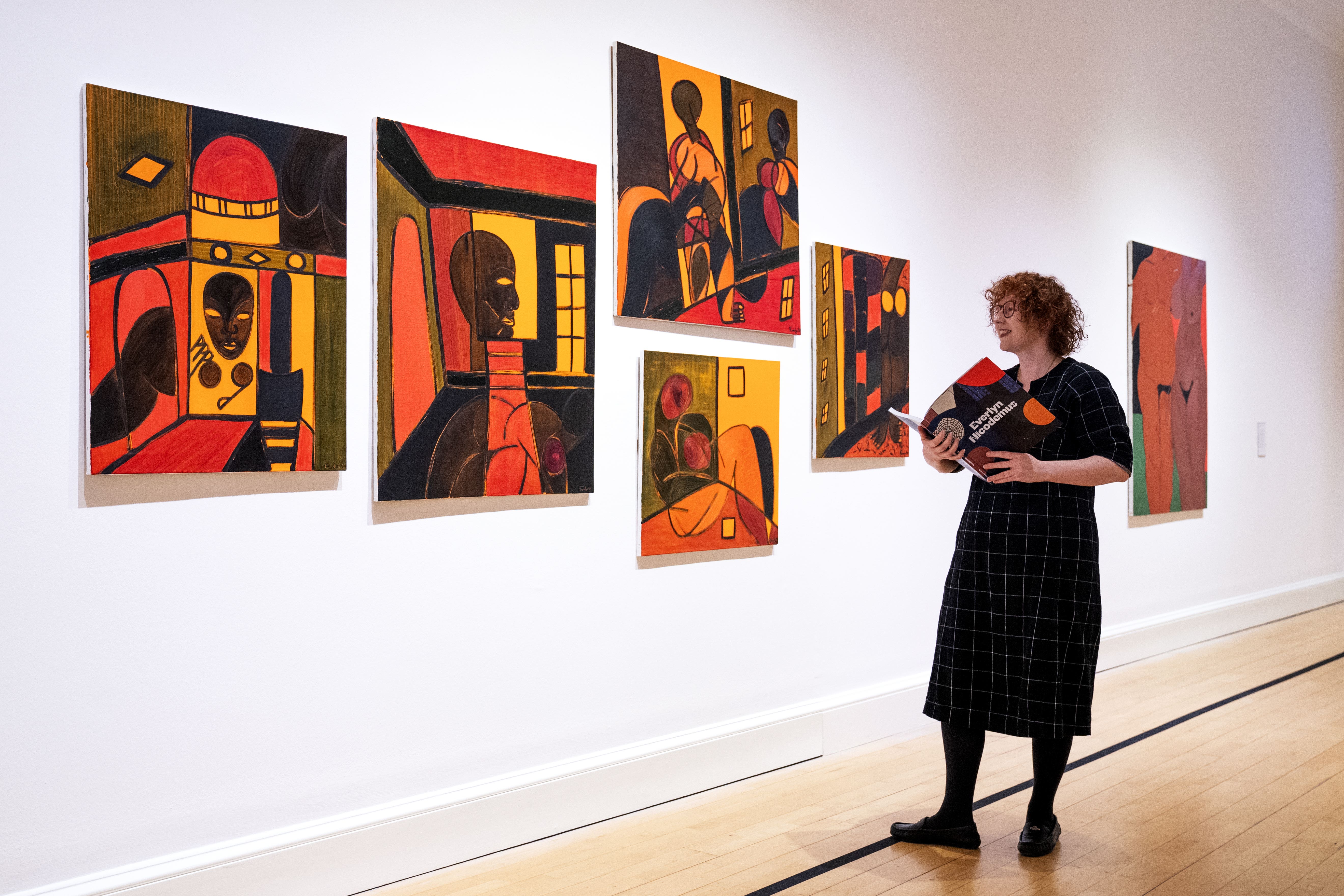 Stephanie Straine standing next to some of Nicodemus’ paintings (Jane Barlow/PA)