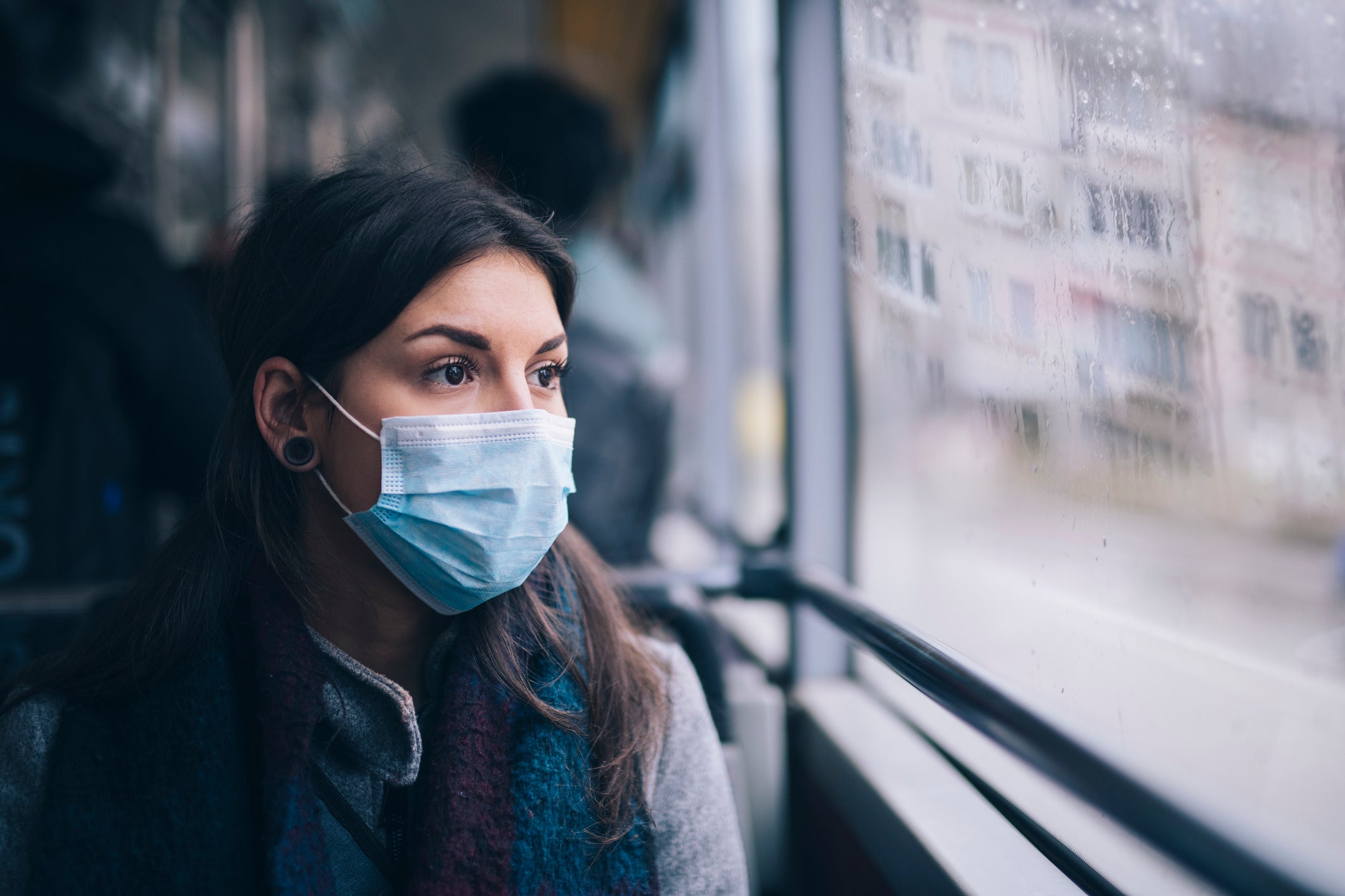 A woman wears a face mask while she rides on public transportation. The Centers for Disease Control and Prevention is recommending that Americans mask up ahead of the winter flu season. Masks help to prevent the spread of respiratory viruses.