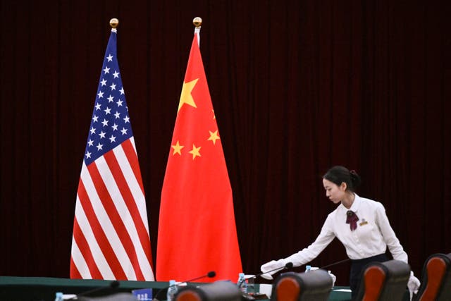 <p>An assistant stands next to China and USA flags in the southern Chinese city of Guangzhou</p>