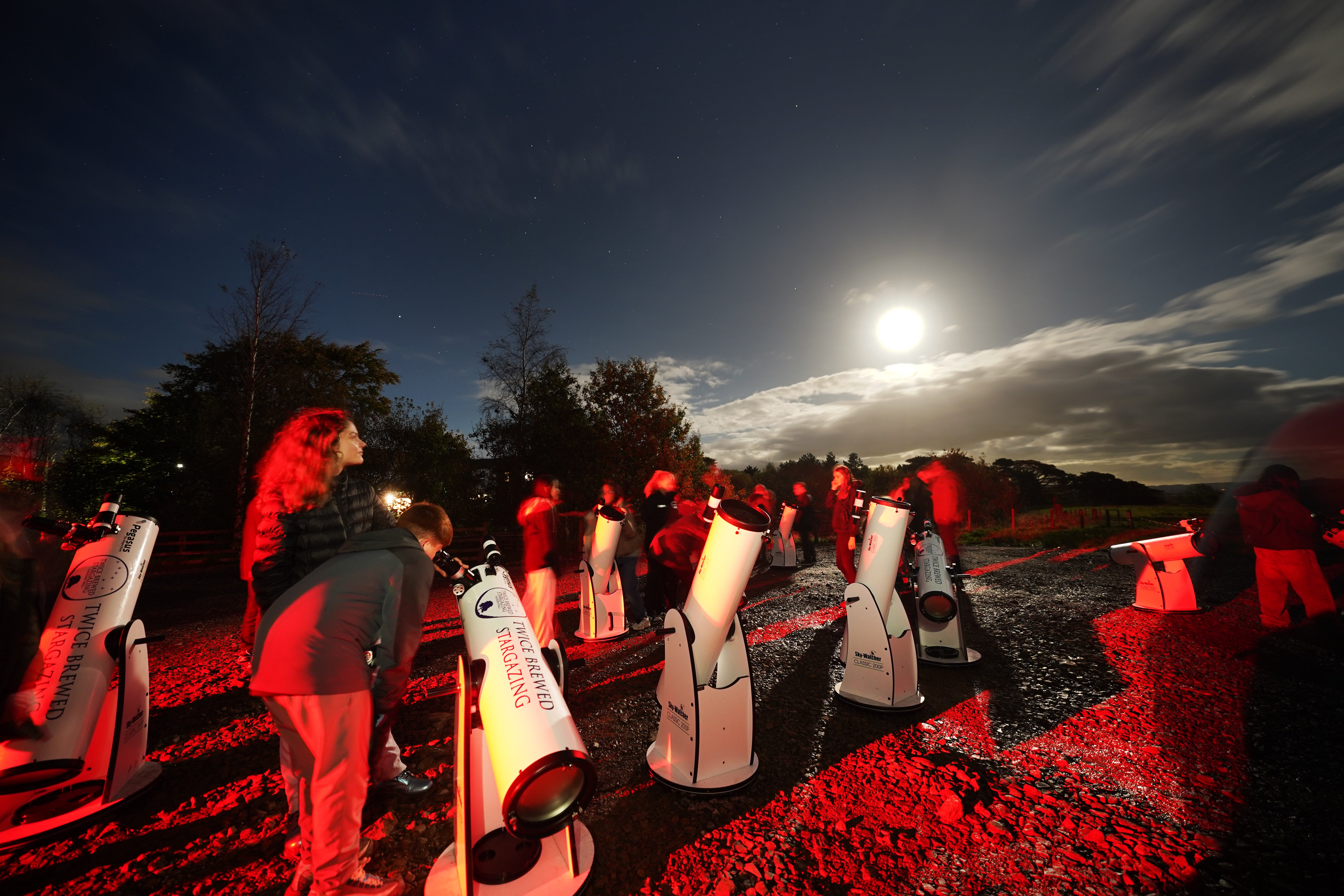 A group of stargazers use telescopes to catch a glimpse of the Comet A3 above the Twice Brewed Inn in the Northumberland International Dark Sky Park (Owen Humphreys/PA)