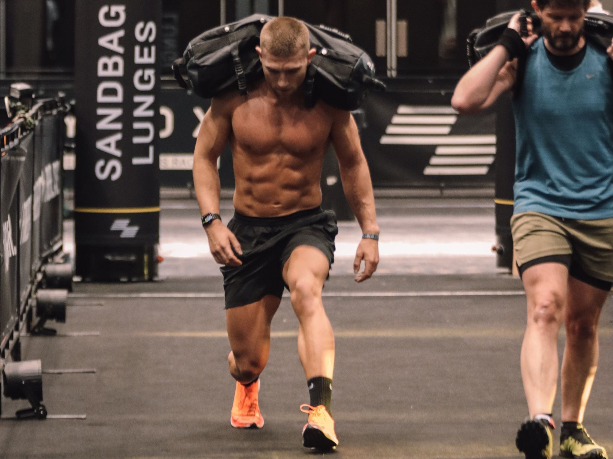 Hyrox UK master trainer Jake Dearden performing weighted lunges during a Hyrox race