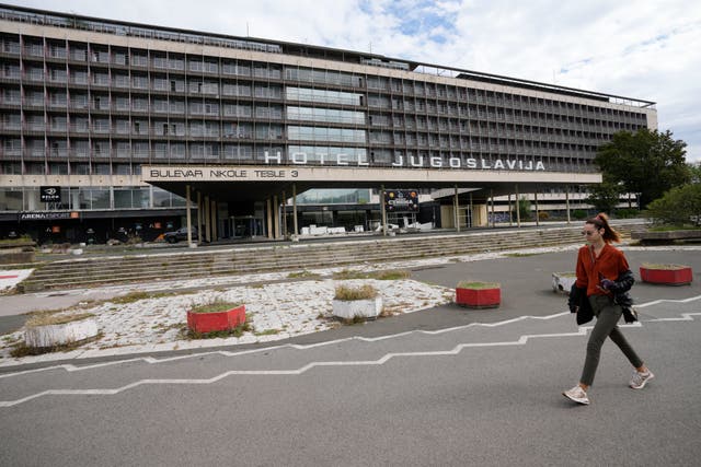 <p>A woman walks past Hotel Yugoslavia, once a symbol of progress in the former socialist state of Yugoslavia</p>