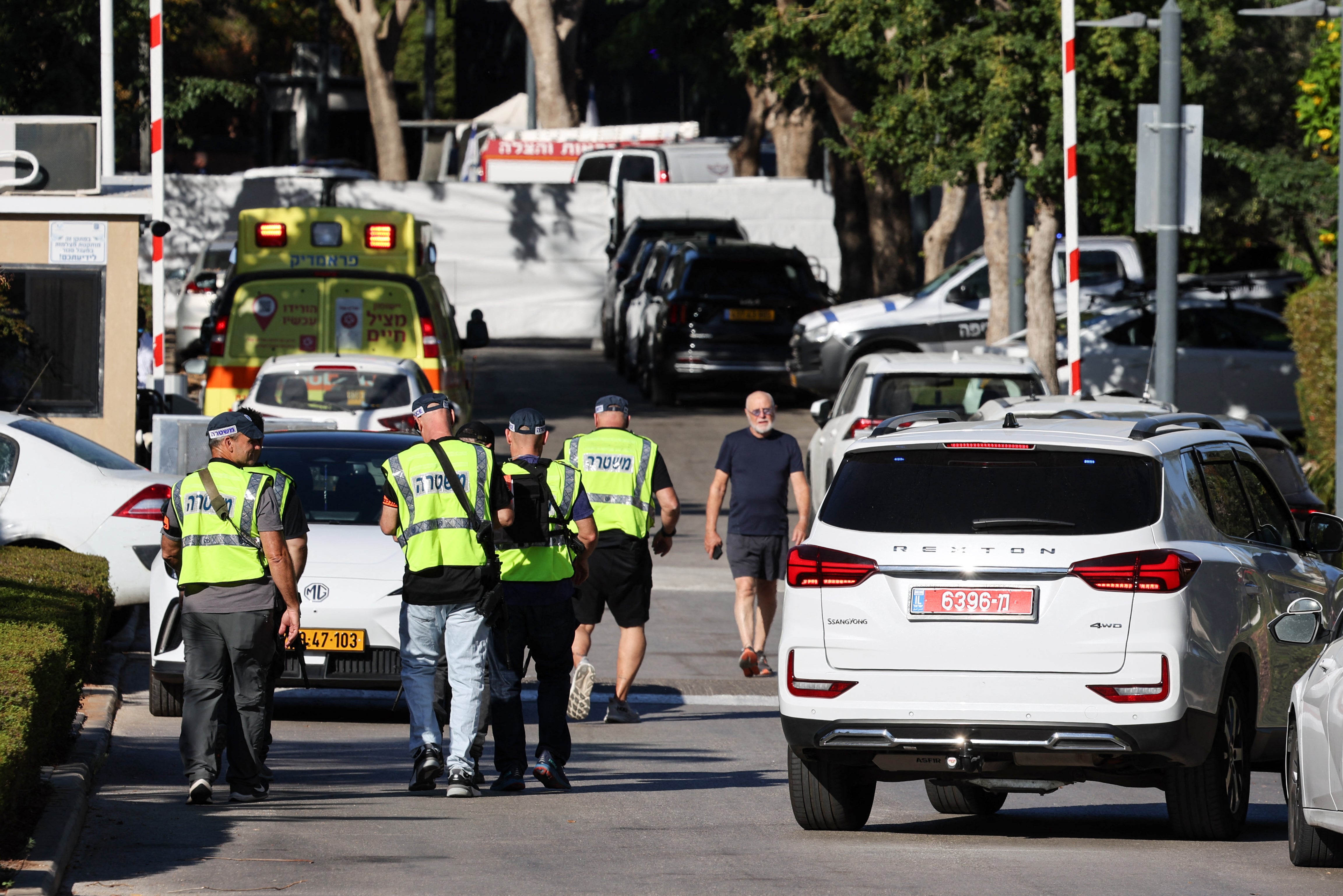 An ambulance can be seen as Israeli security forces walk along a street leading to prime minister Benjamin Netanyahu's residence in Caesarea