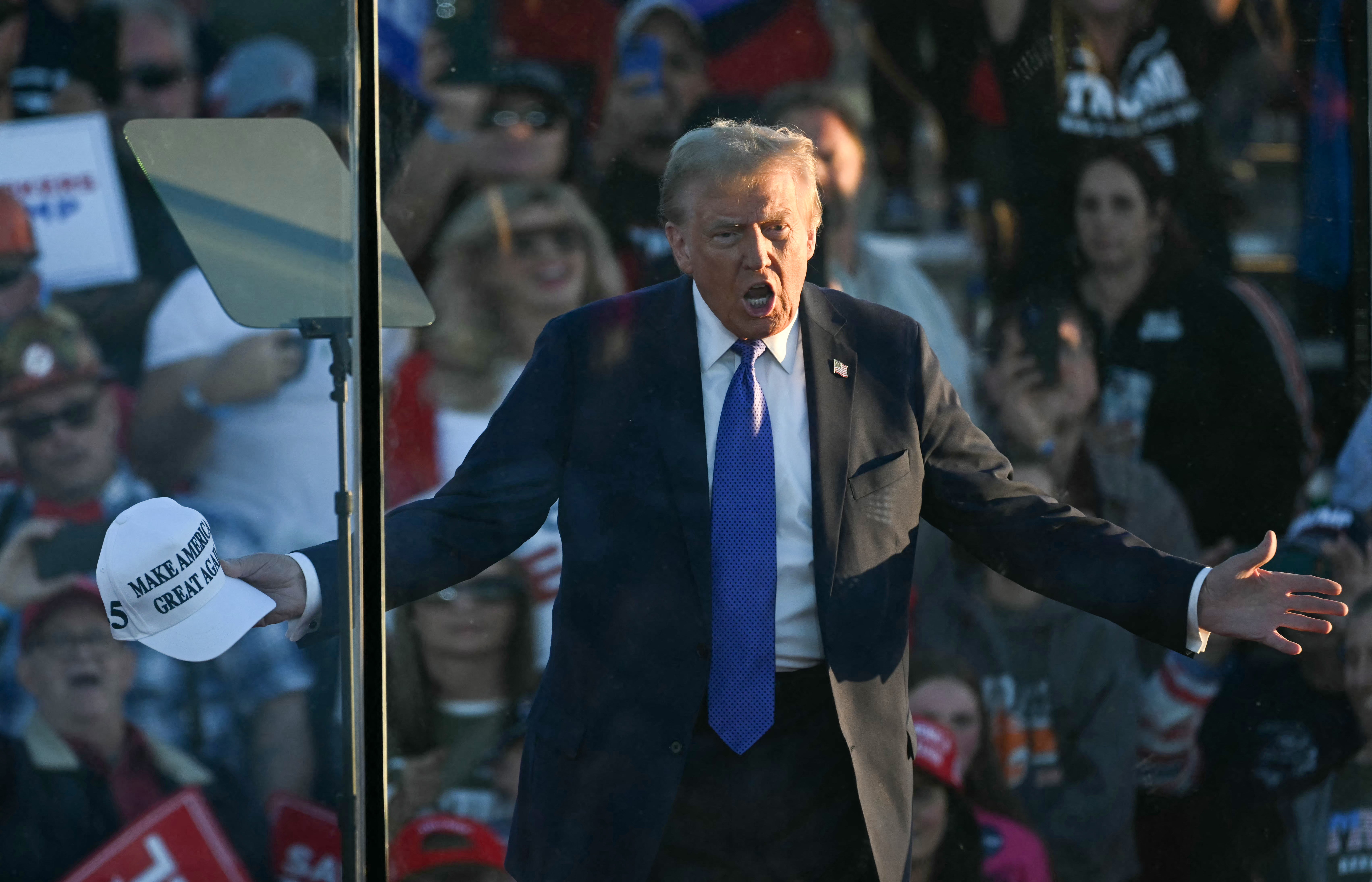 Former US President and Republican presidential candidate Donald Trump speaks behind bulletproof glass during a campaign rally at Arnold Palmer Regional Airport in Latrobe, Pennsylvania, October 19, 2024.