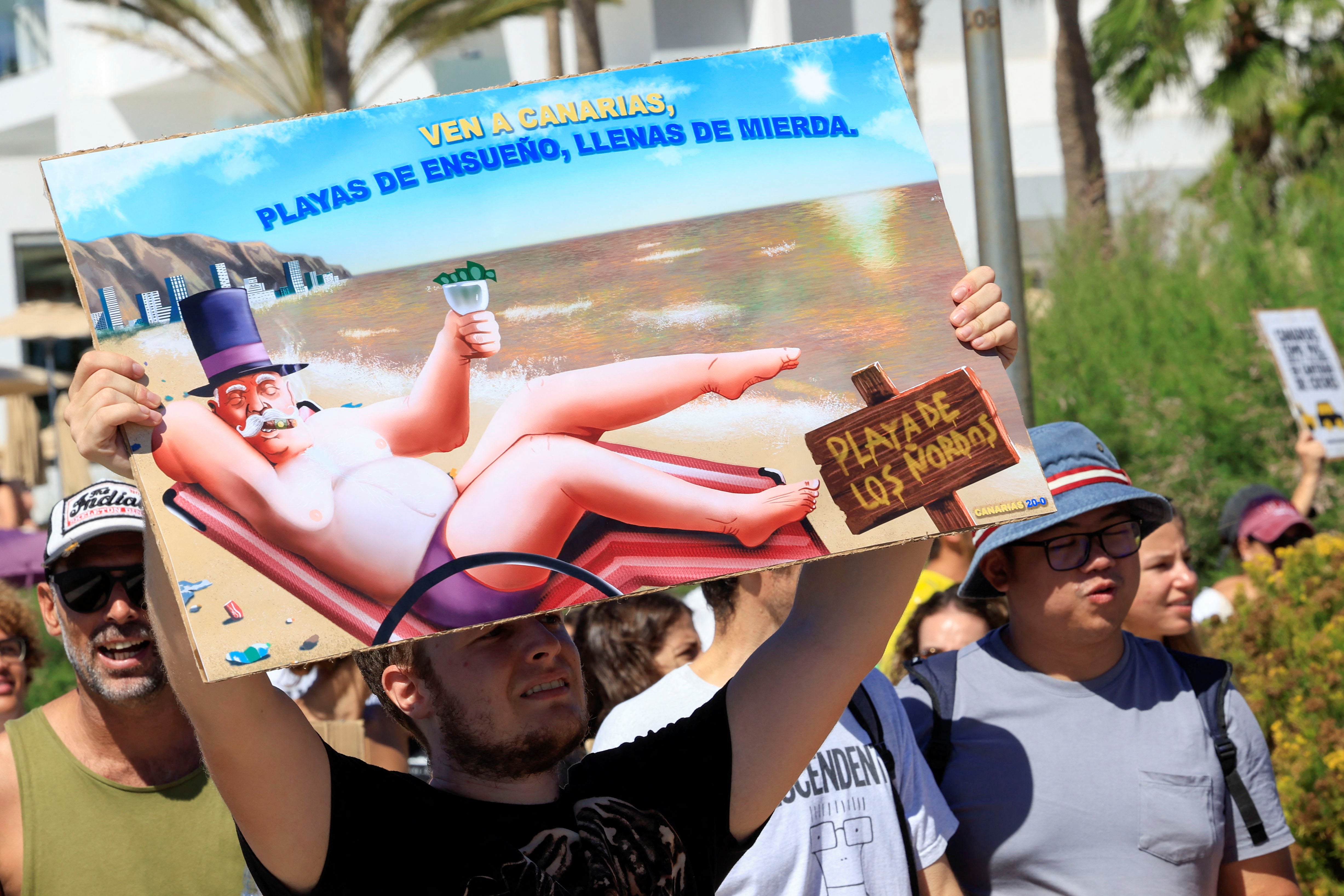 A man shows a sign during a demonstration for a change in the tourism model in the Canary Islands on the island of Gran Canaria, Spain