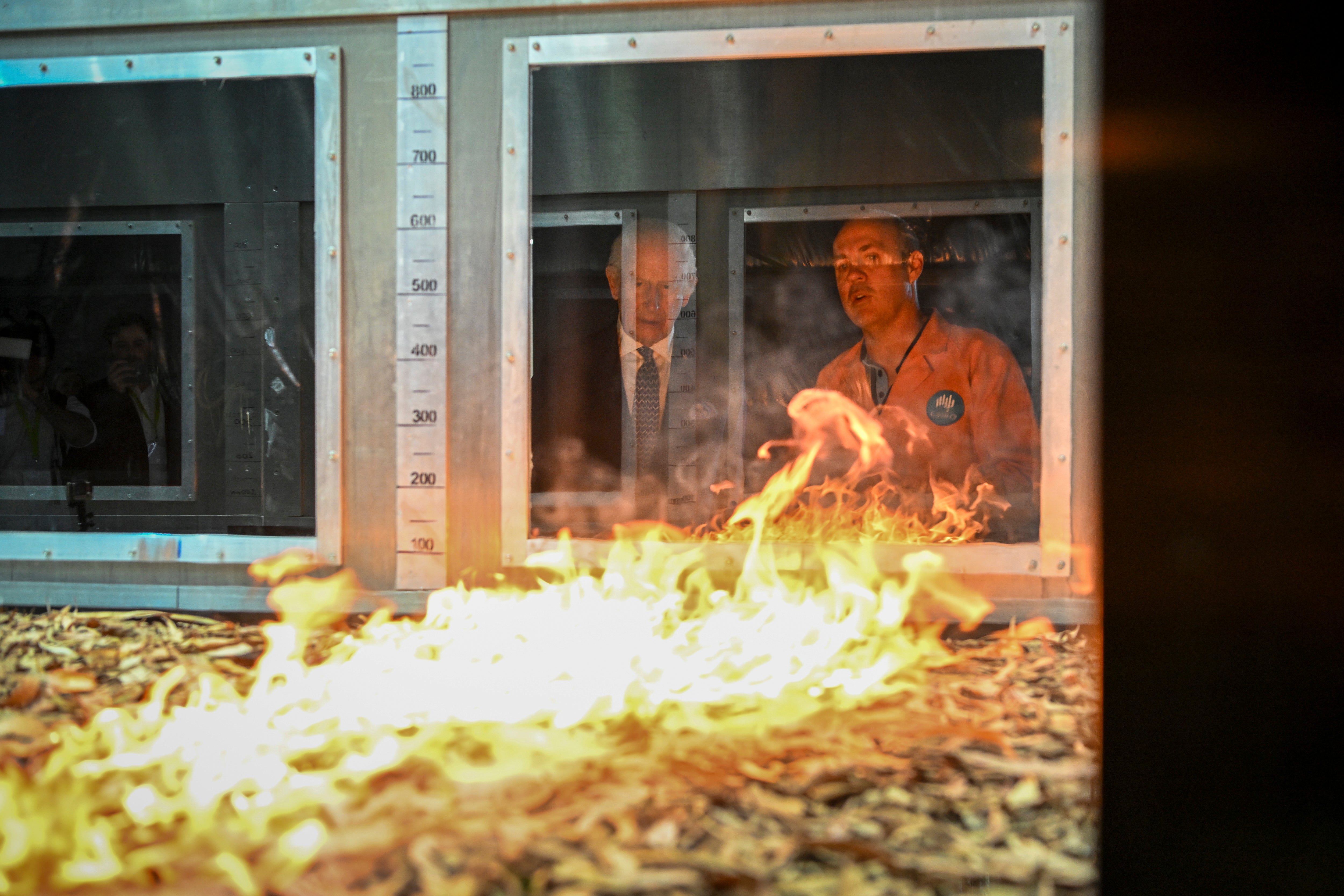 Britain's King Charles III listens to research scientist Dr. Matt Plucinski, right, describe the "Pyrotron" combustion wind tunnel during a visit to the CSIRO National Bushfire Behaviour Research Laboratory in Canberra