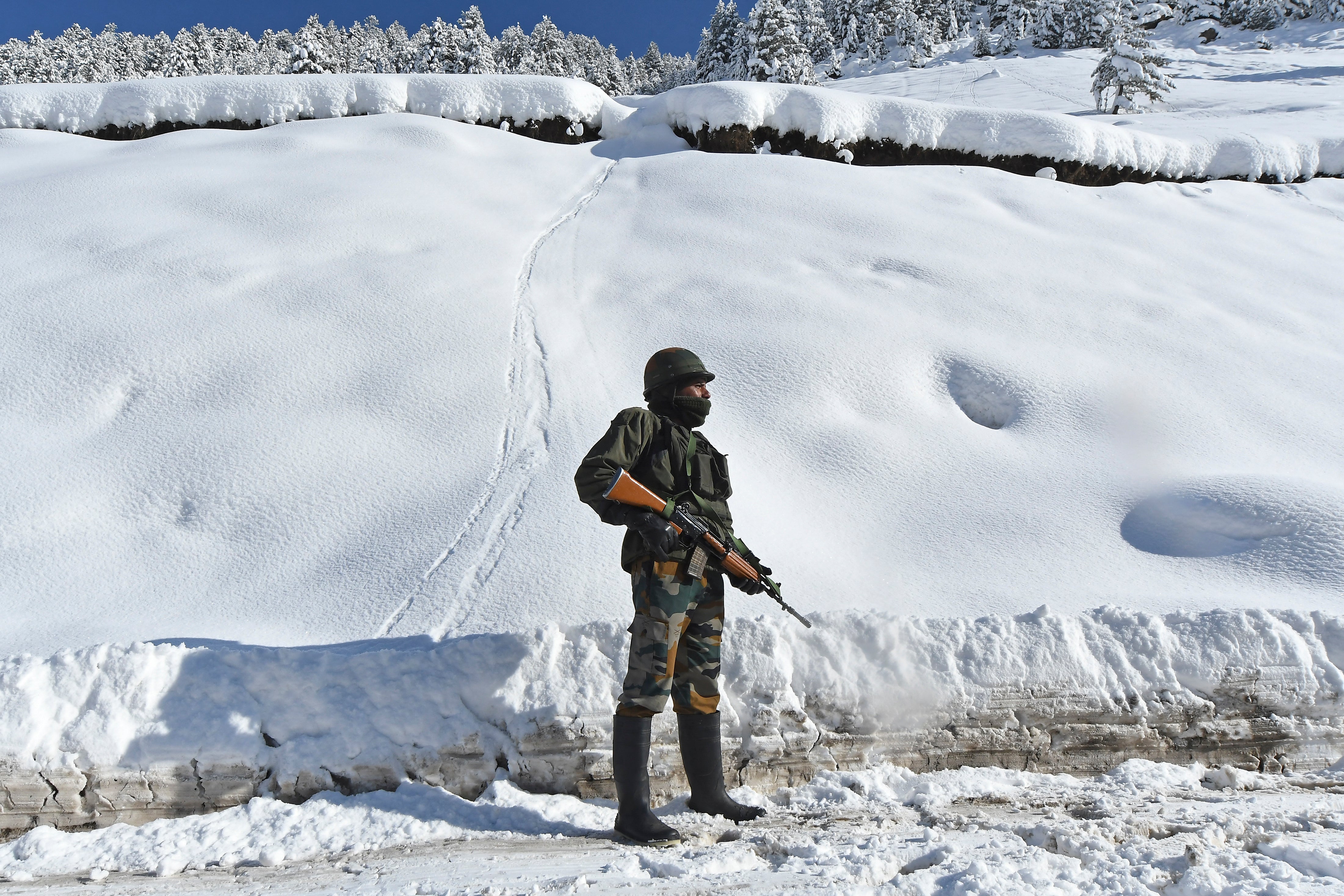 An Indian soldier stands on a road near Zojila mountain pass that connects the restive Himalayan valley of Kashmir to the federal territory of Ladakh bordering China on 28 February 2021