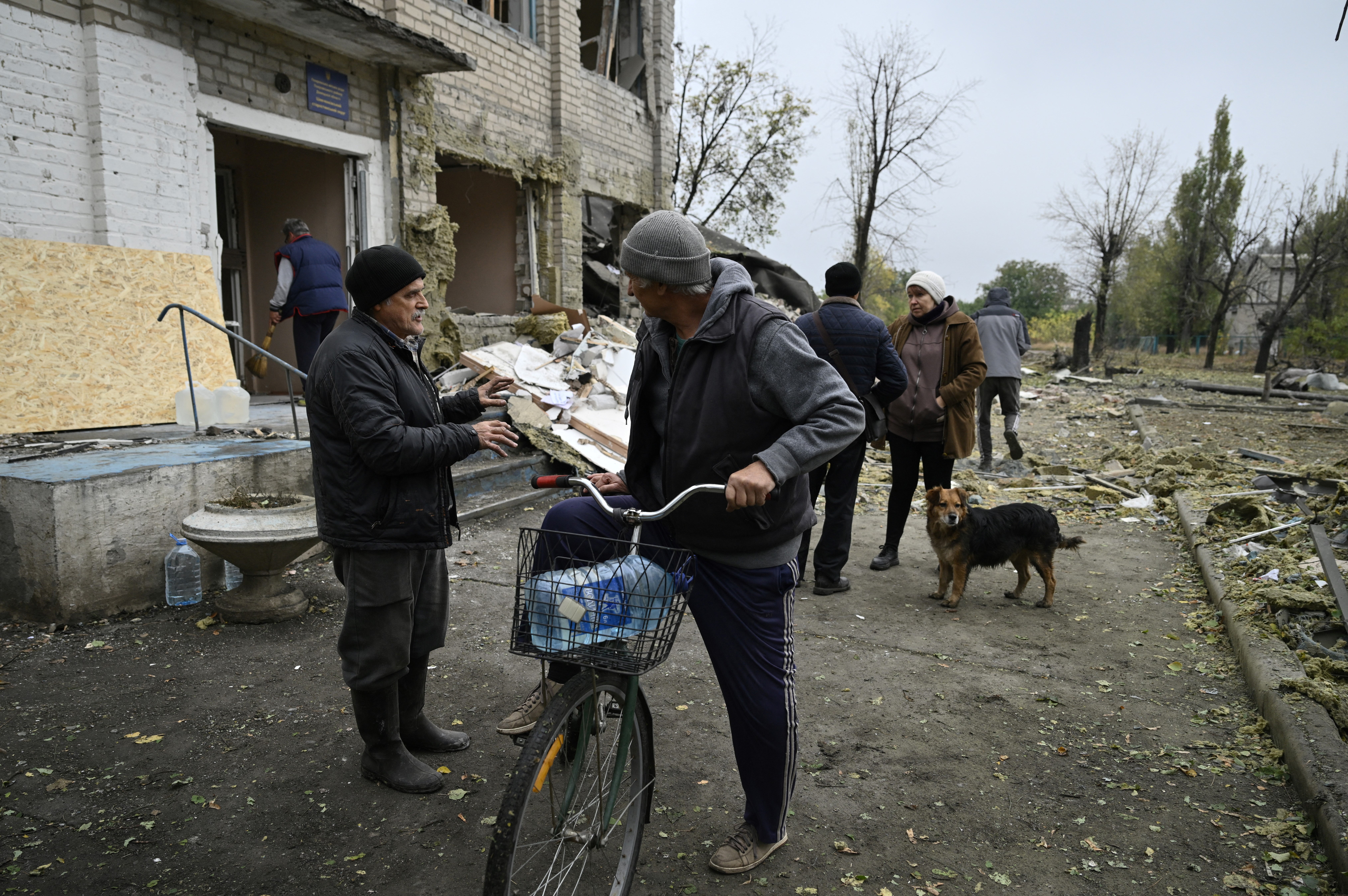 Local residents catch up as they stop in front of a local administrative building, destroyed following a strike on the village Shevchenko in Donetsk