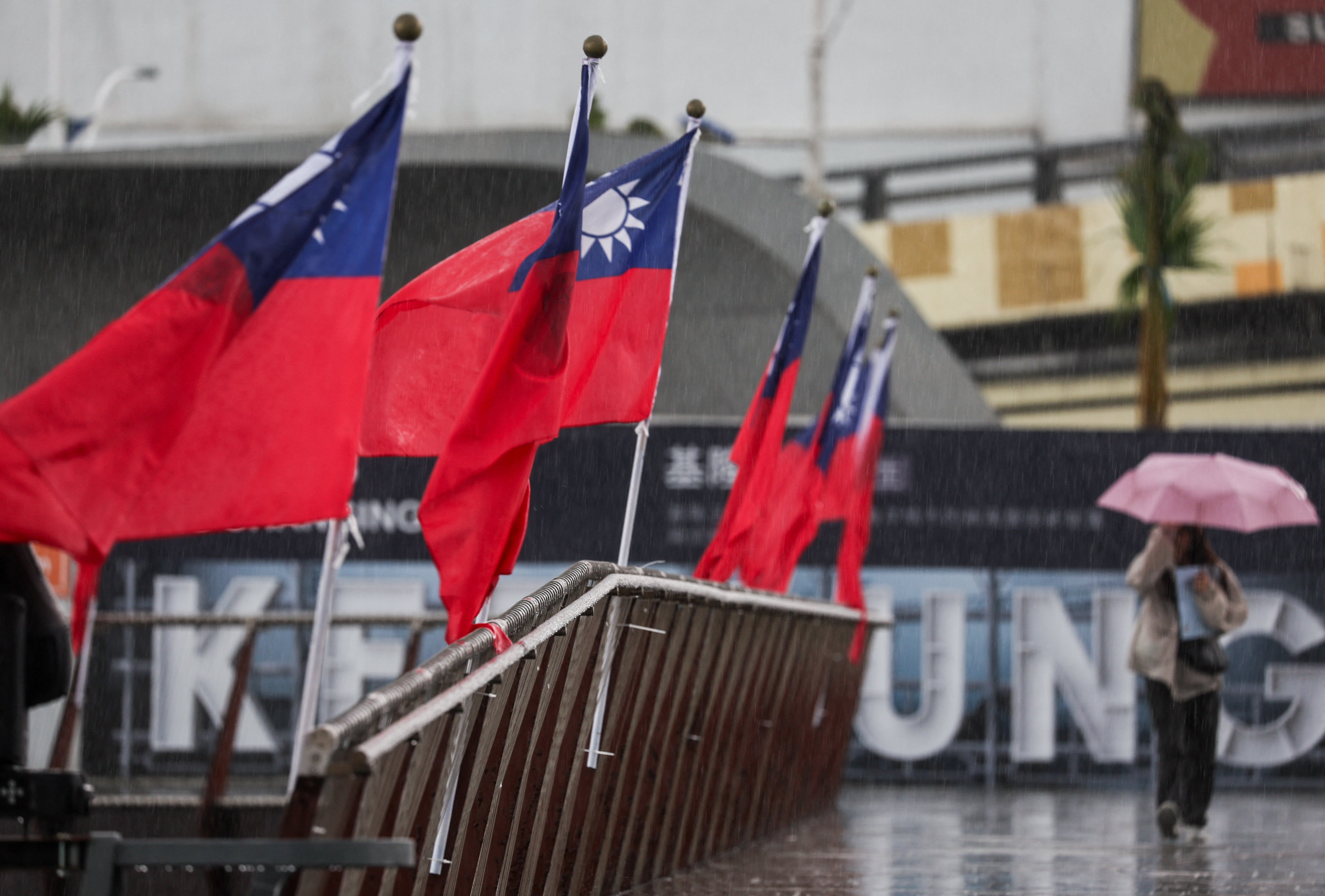 A woman walks past a Taiwanese national flag at Maritime Plaza in Keelung on 22 October 2024. China's military began a live fire exercise near Taiwan, maintaining pressure on the self-ruled island after staging large-scale drills and President Xi Jinping called for troops to prepare for war