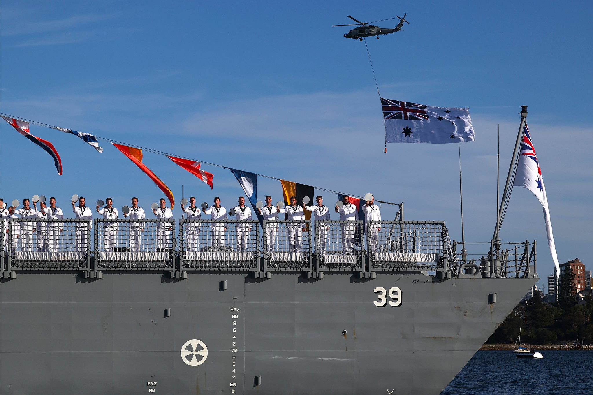 Crew members of the Royal Australian Navy's HMAS Hobart, salute as King Charles III and Queen Camilla conduct an Australian Navy fleet review in Sydney Harbour.