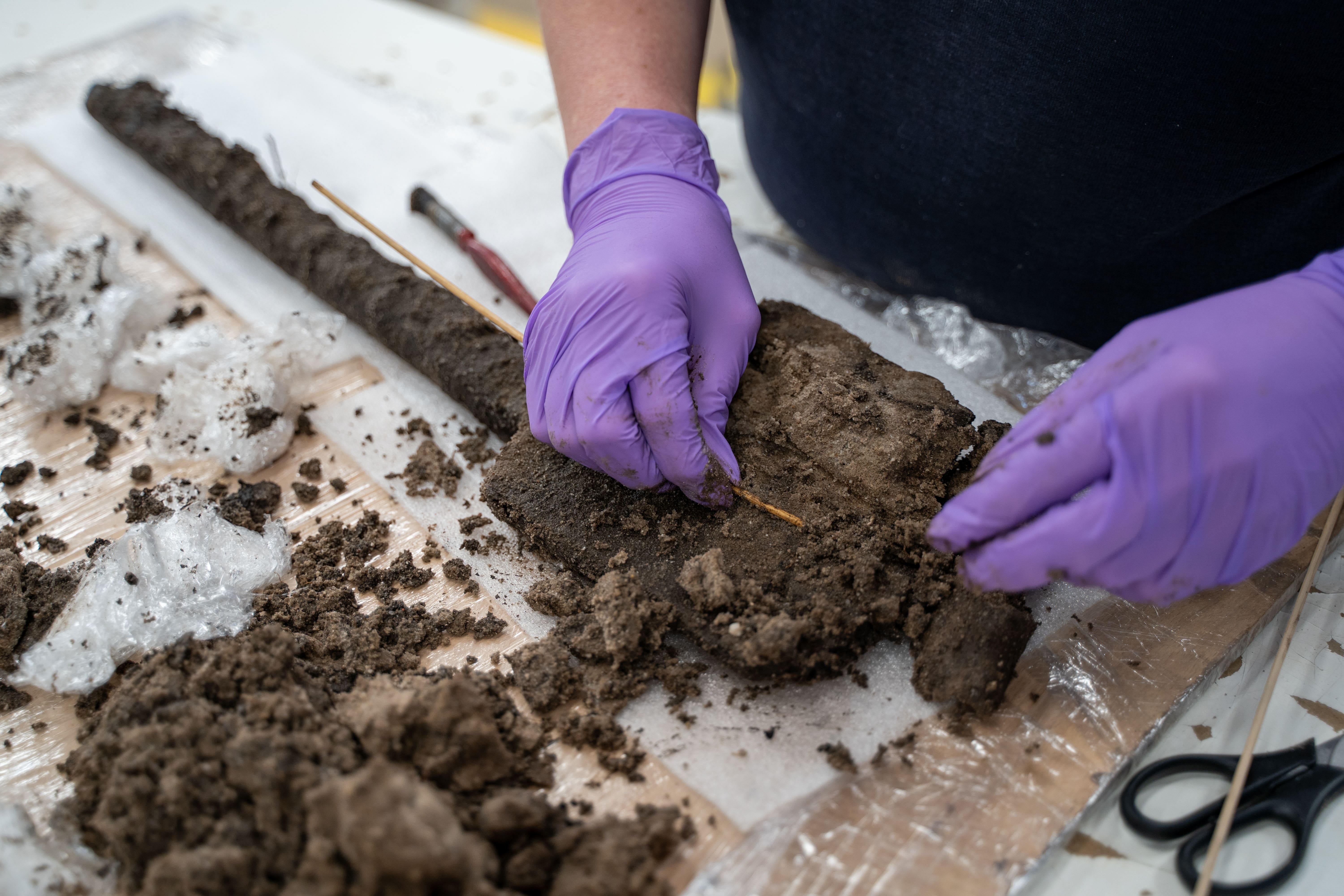 Experts from Wessex Archaeology carefully clean the spade of excess mud as part of the conservation process (Wessex Archaeology/PA)