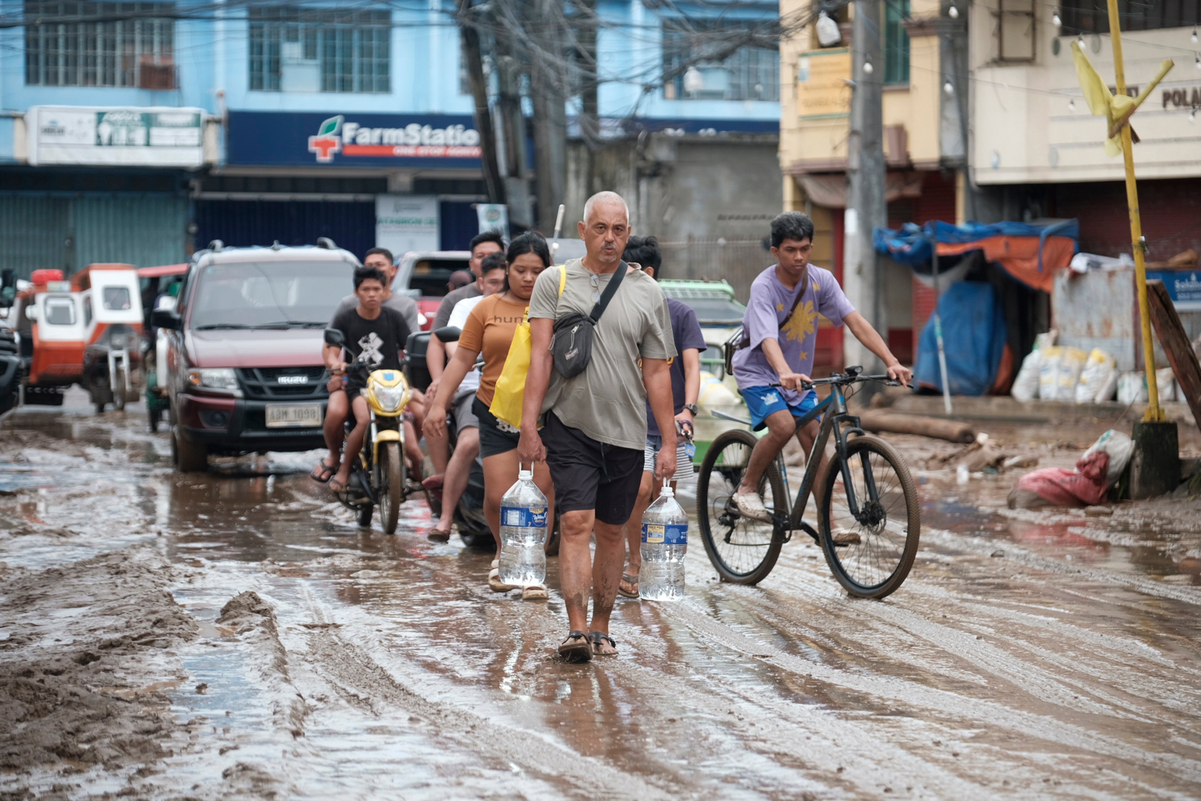 People use a muddied road after floods caused by Trami in Polangui, Philippines, on 23 October 2024