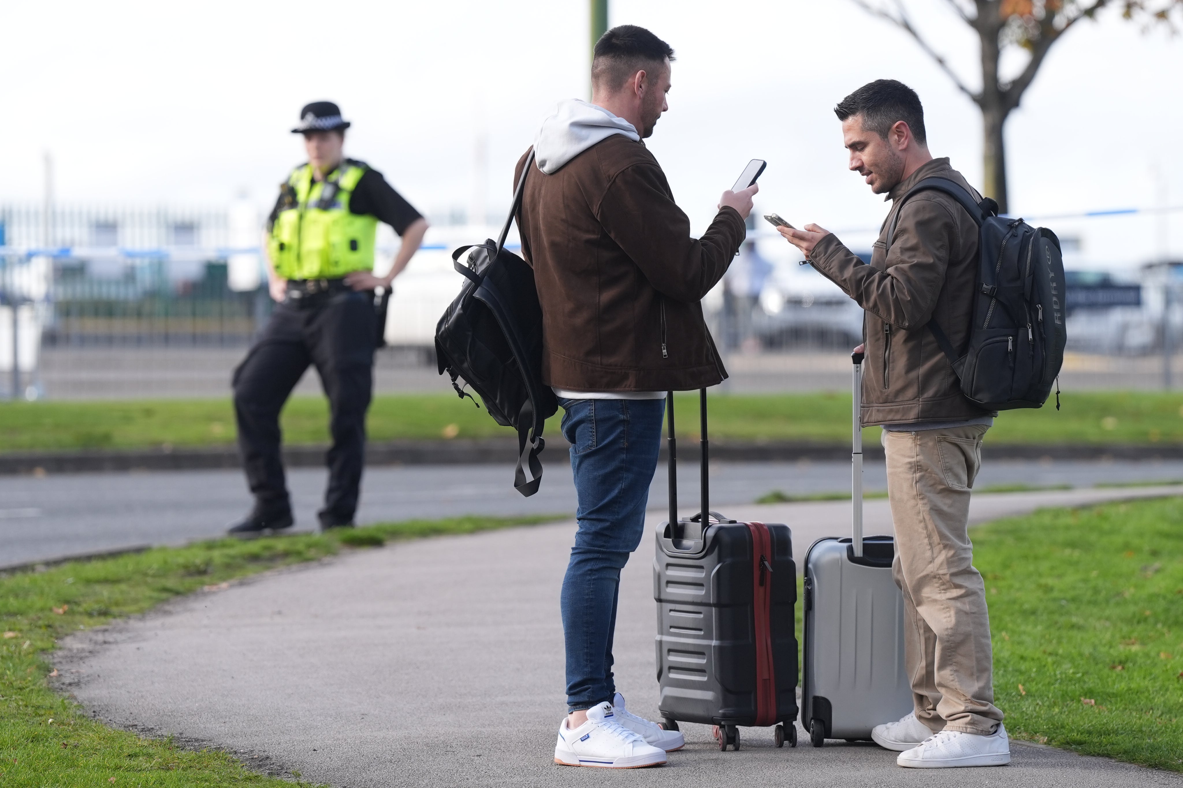 Passengers wait outside Birmingham Airport as flights were canceled and delayed following a bomb scare