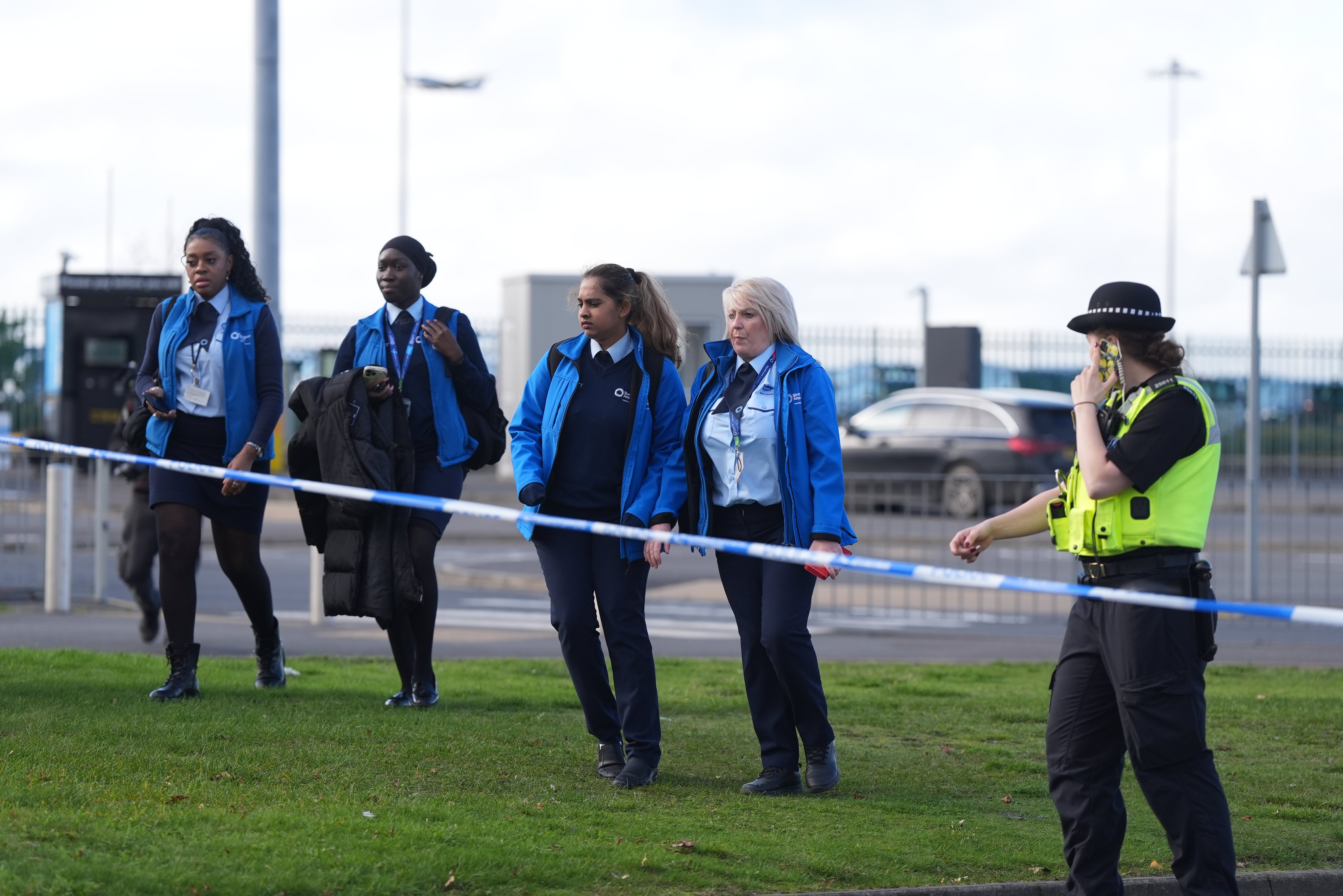 After a bomb scare, airport employees wait next to a police cordon