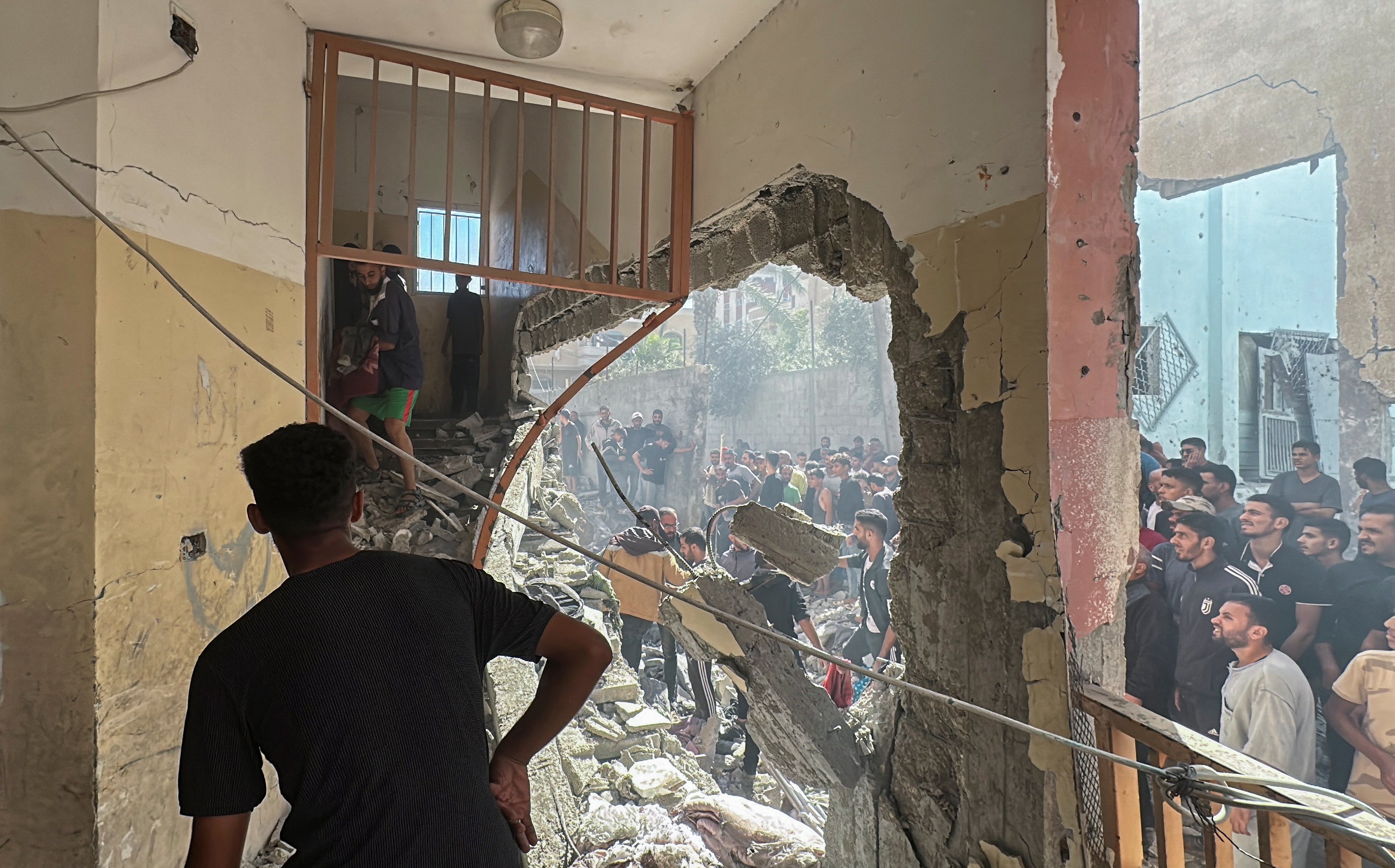 Palestinians inspect the site of an Israeli strike on a school sheltering displaced people