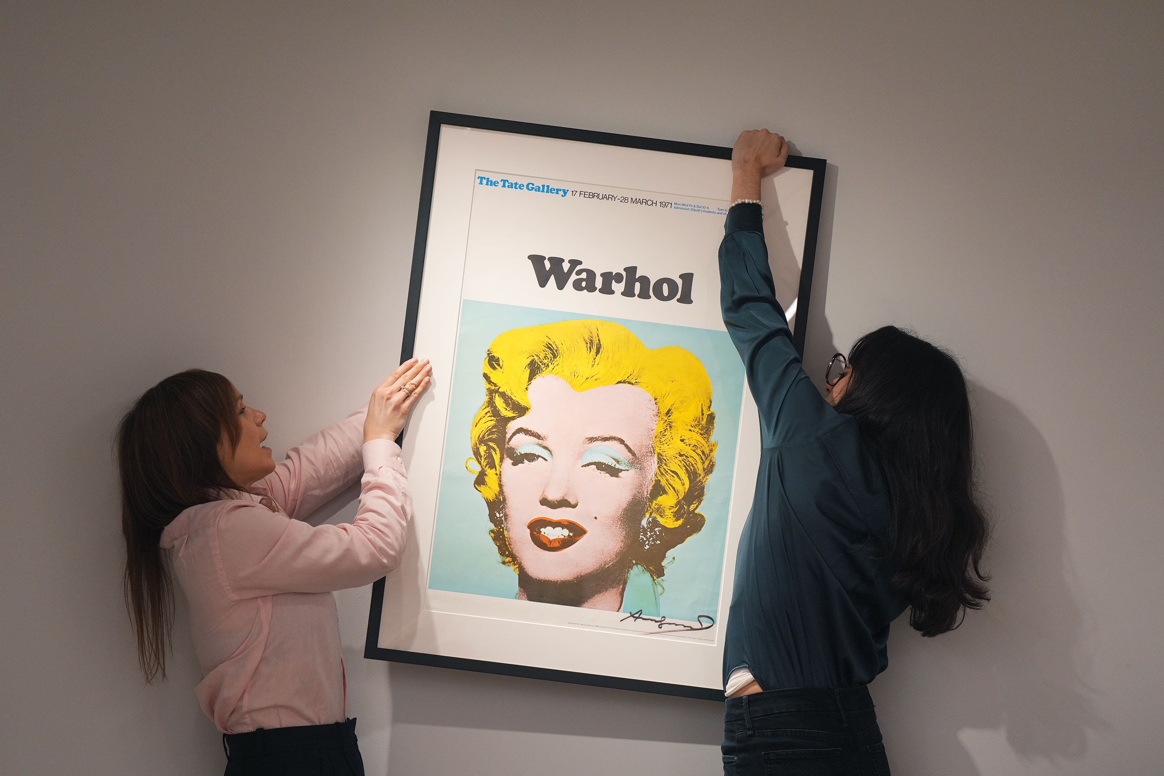 Members of gallery staff position a signed Tate Gallery poster by Andy Warhol, Marilyn Monroe, 1971, during a photo call at the new Shapero Modern gallery (Yui Mok/PA)