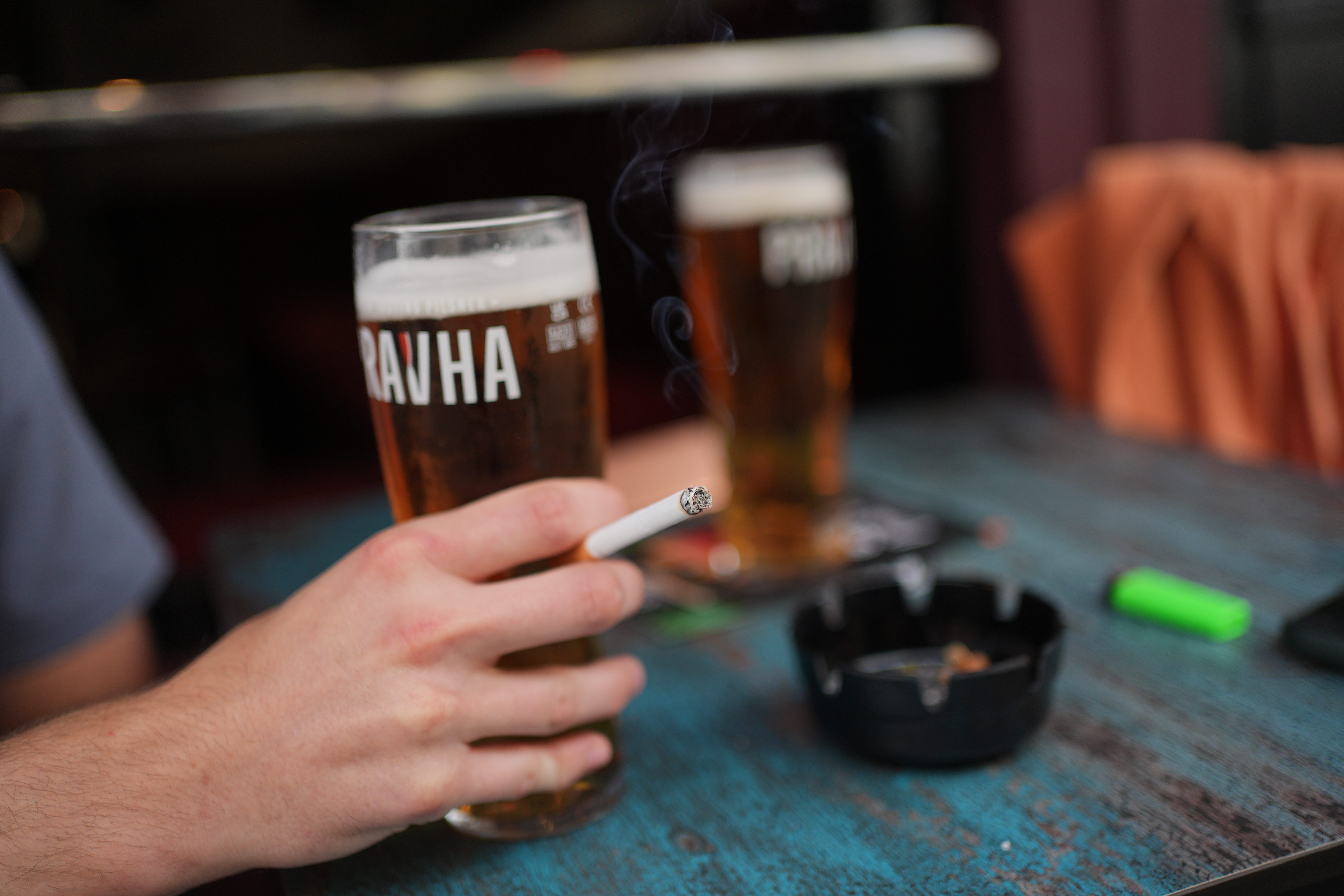 A person smoking a cigarette outdoors in a pub, in Soho, London (Yui Mok/PA)