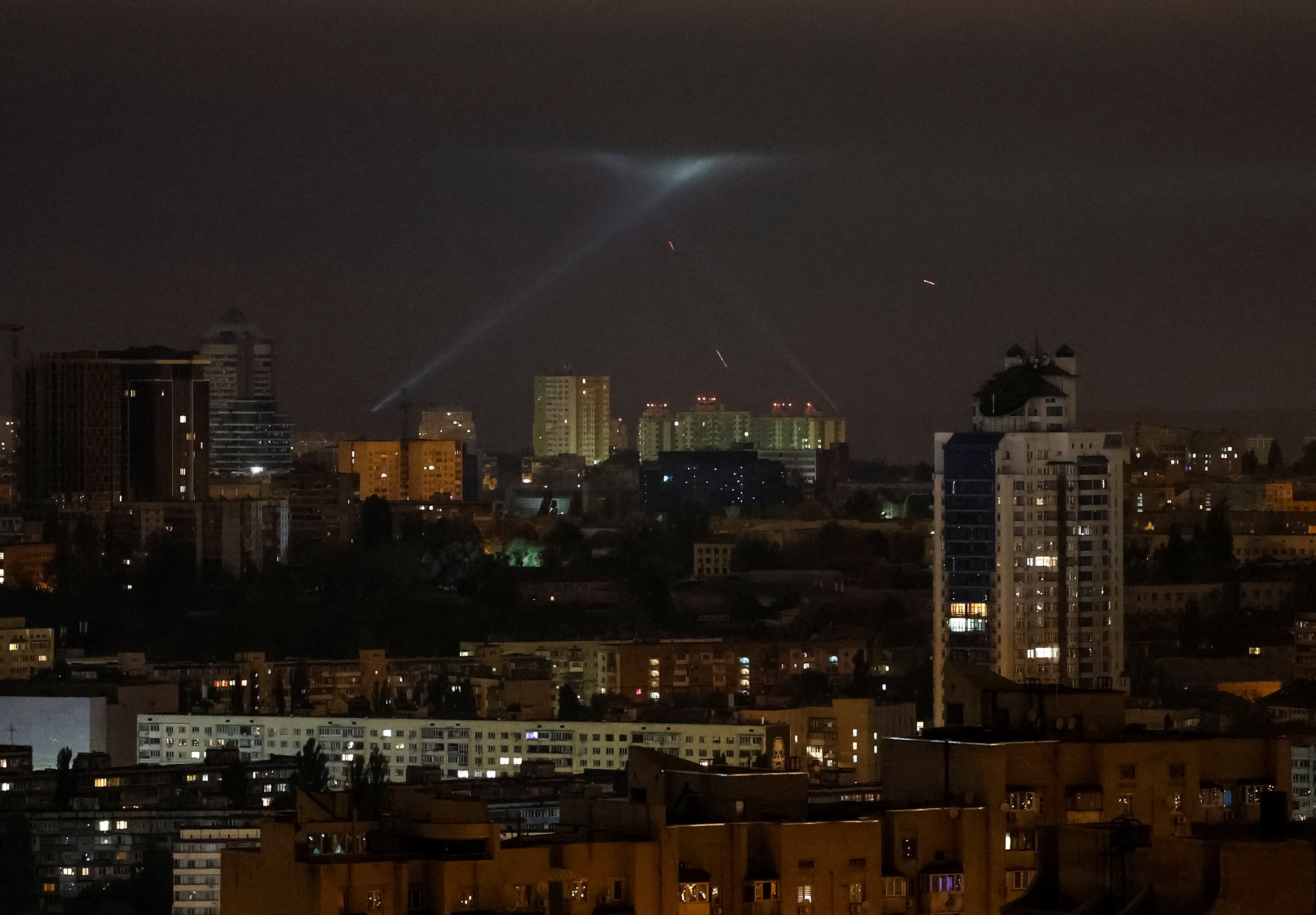 Ukrainian service personnel use searchlights as they search for drones in the sky over the city