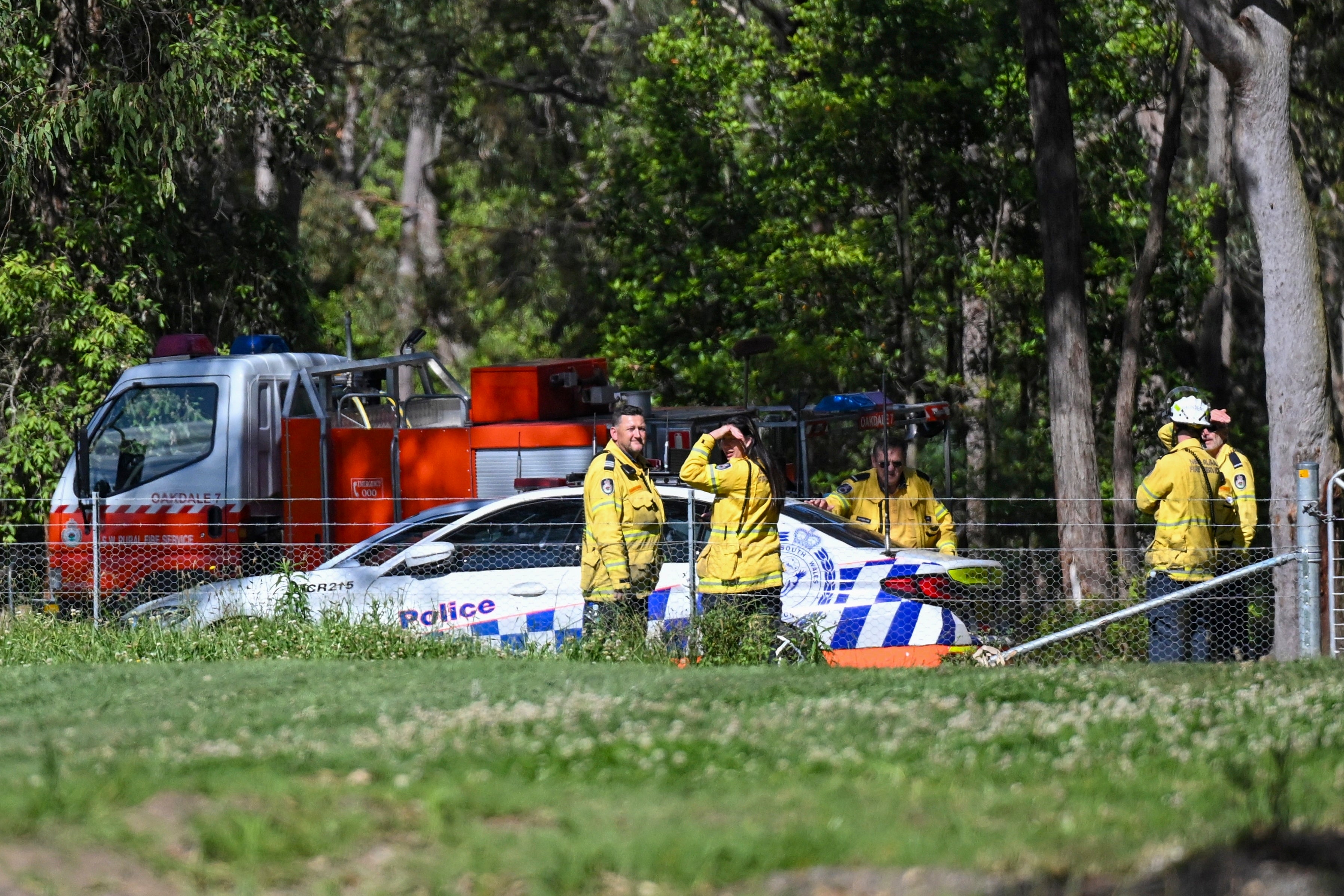 Police and firefighters stand near the aircraft crash site southwest of Sydney, Australia, on 26 October 2024