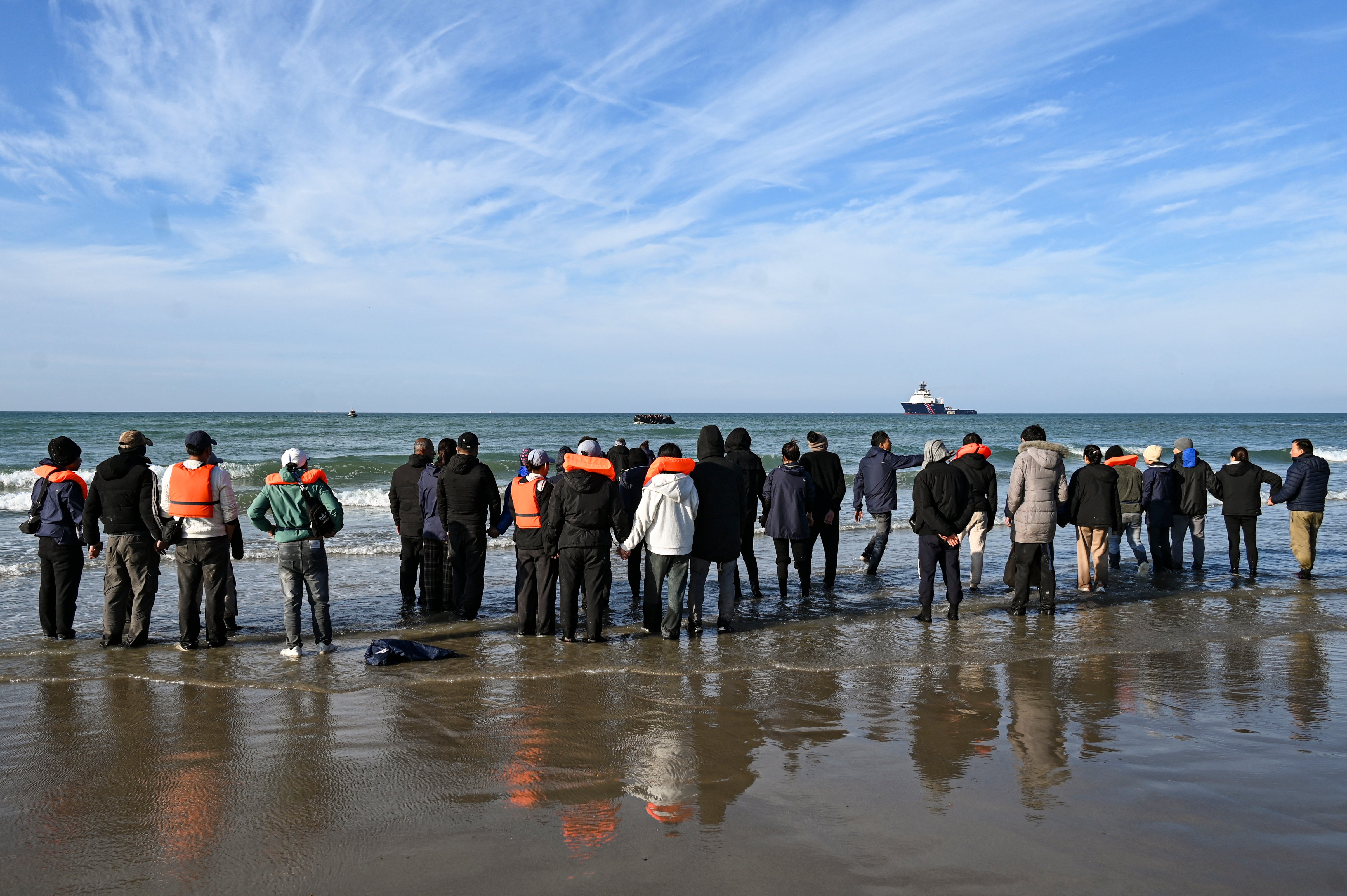 Migrants wait to board a smugglers' boat in order to attempt crossing the English channel off the beach of Audresselles, northern France on October 25, 2024.